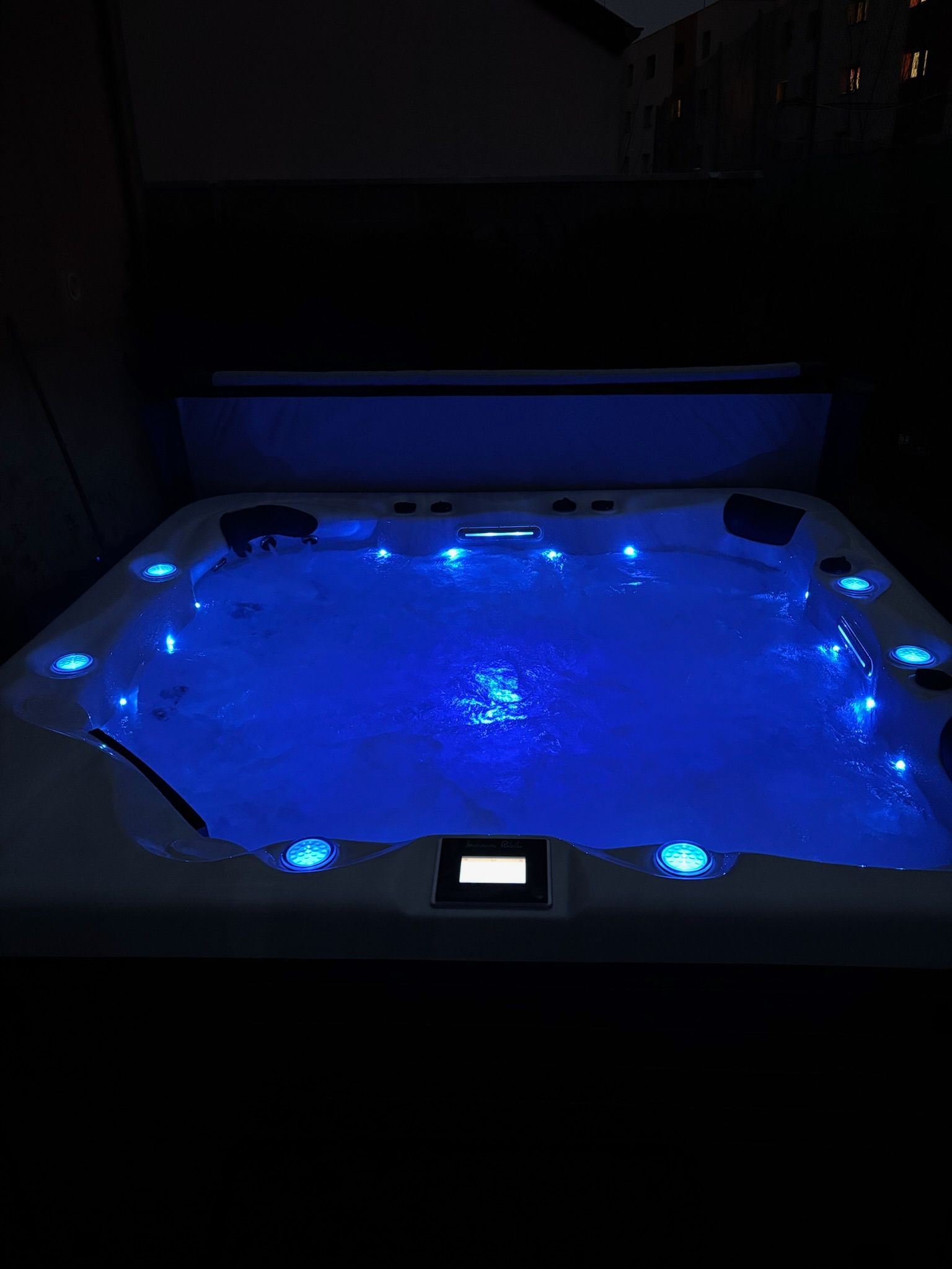 Un bain à remous est éclairé la nuit avec des lumières bleues.