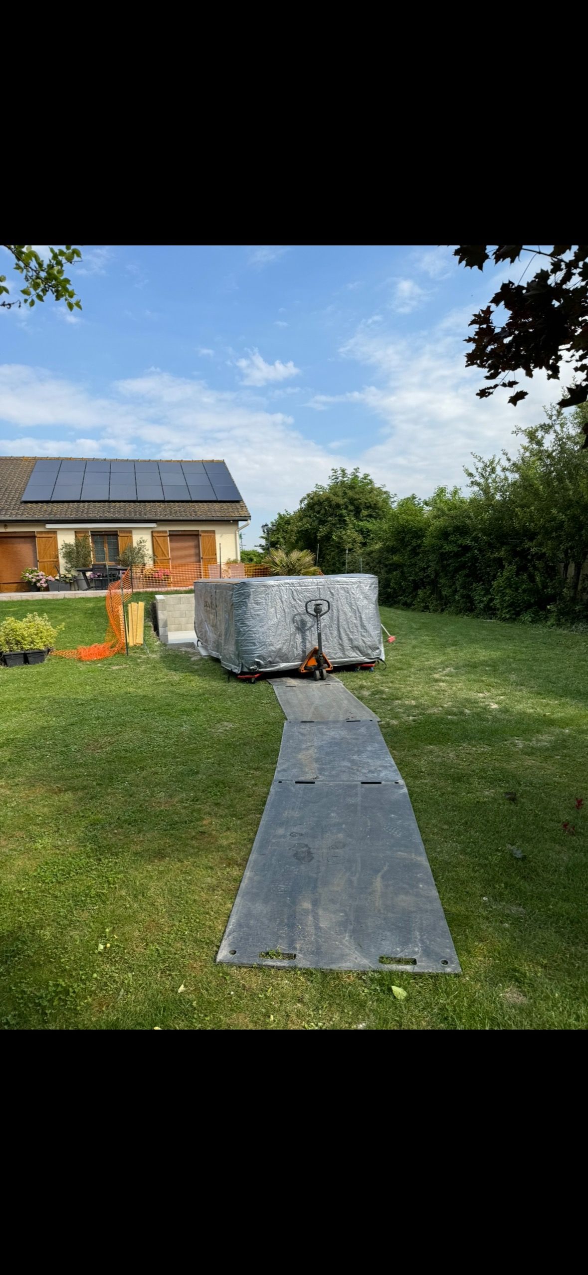 Un grand conteneur est posé sur une pelouse verte luxuriante devant une maison.