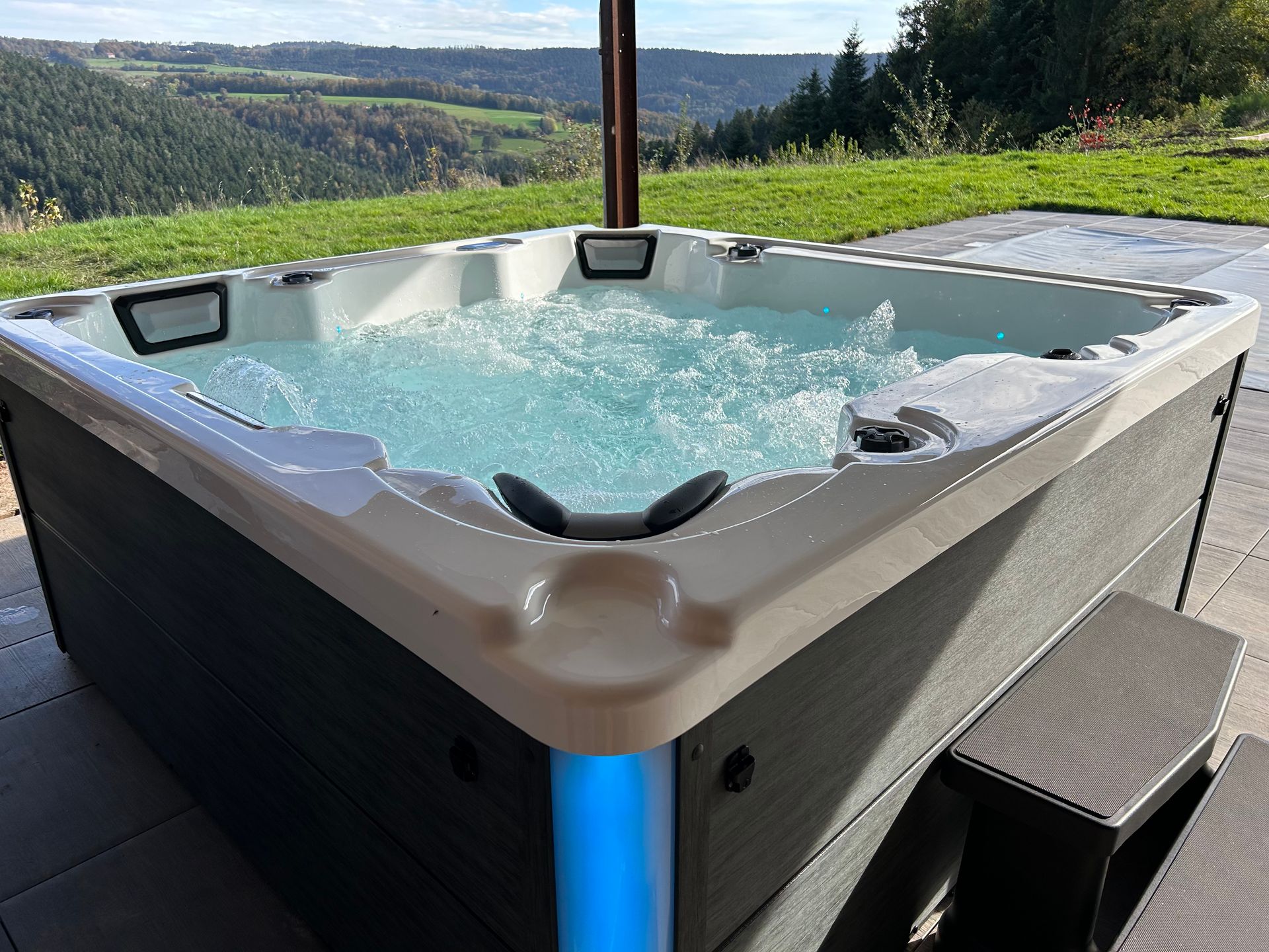 Un bain à remous est installé sur une terrasse avec vue sur les montagnes en arrière-plan.