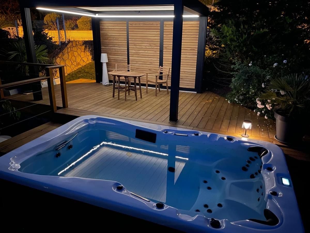Un bain à remous est posé sur une terrasse en bois la nuit.