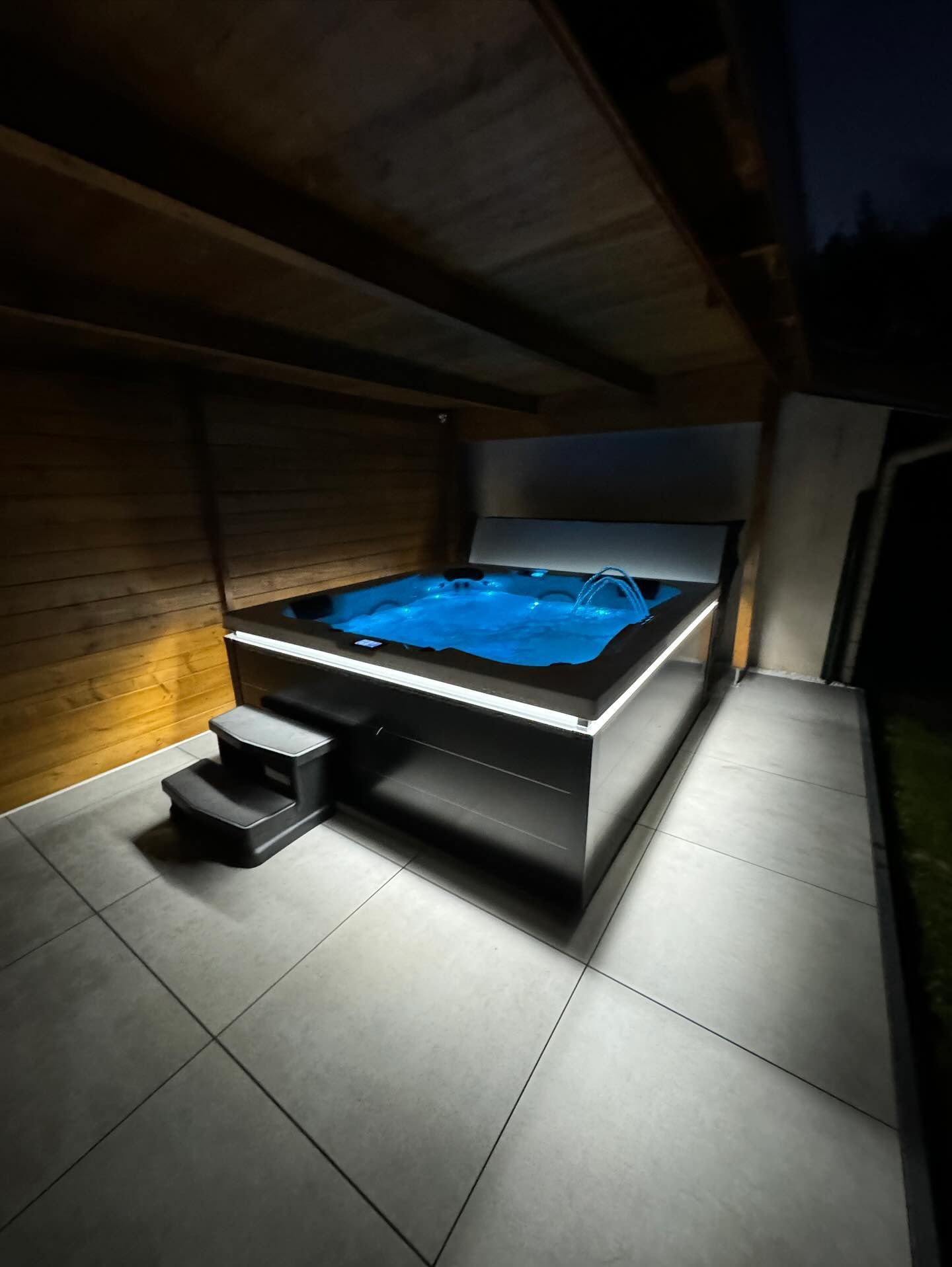 Un jacuzzi en acier inoxydable est éclairé la nuit