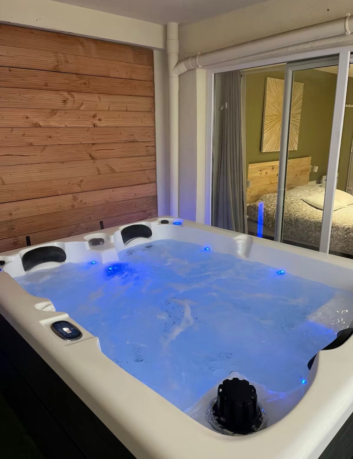 Un grand bain à remous est installé dans une pièce à côté d'une fenêtre.