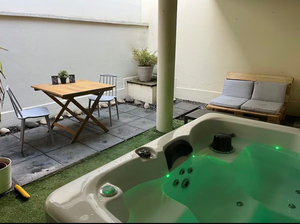 Un bain à remous est installé sur une terrasse à côté d'une table et de chaises.