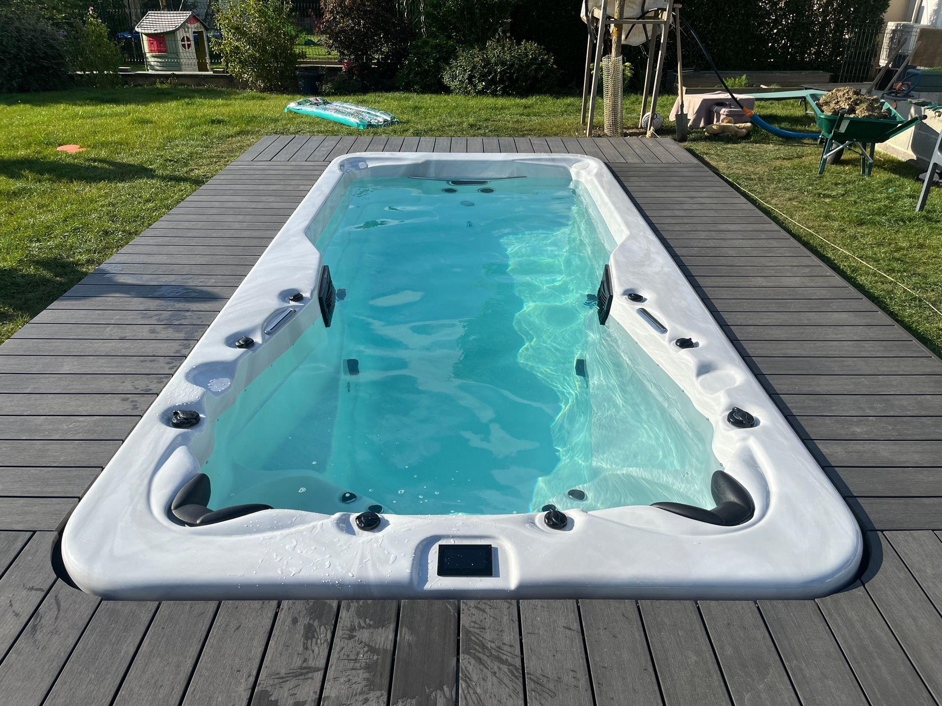 Une grande piscine est située sur une terrasse en bois.