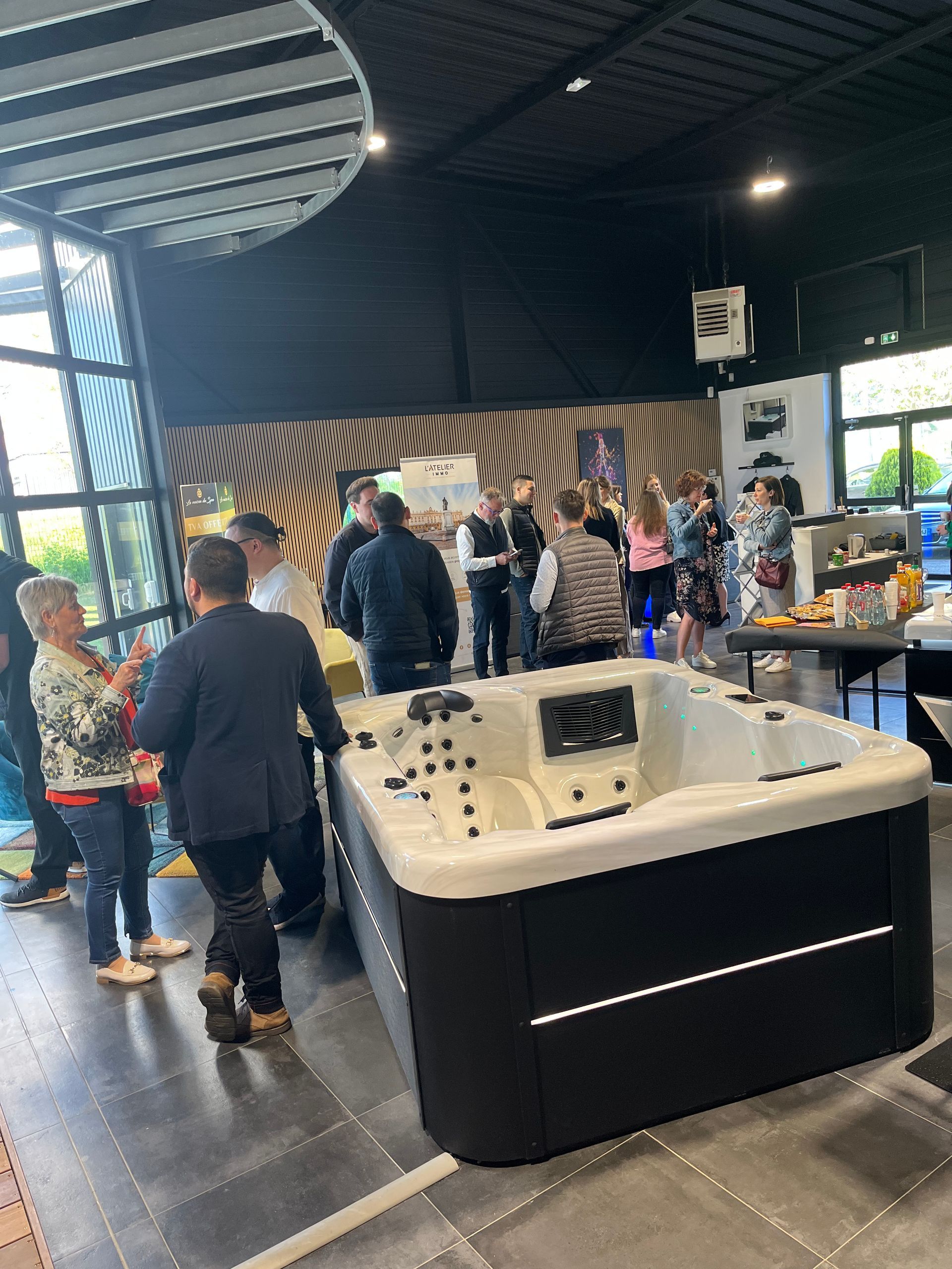 Un groupe de personnes se tient autour d'un bain à remous dans une pièce.