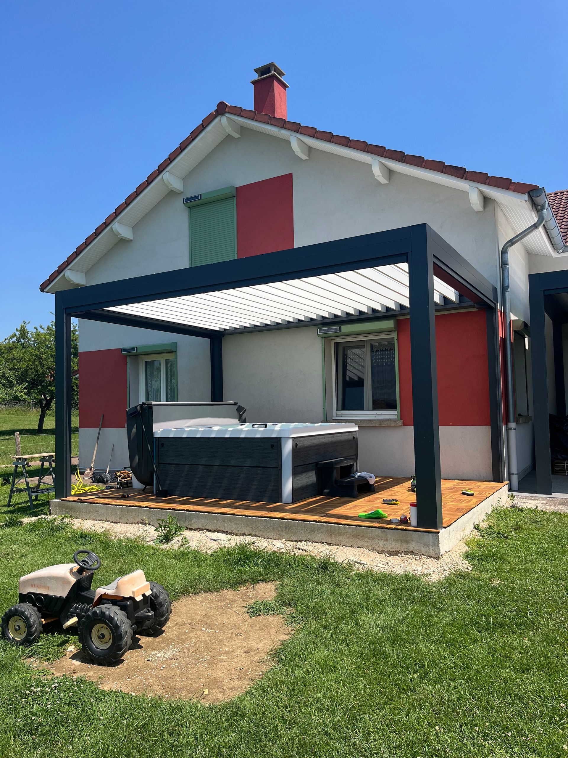 Une maison avec une pergola et un jacuzzi sur la terrasse.