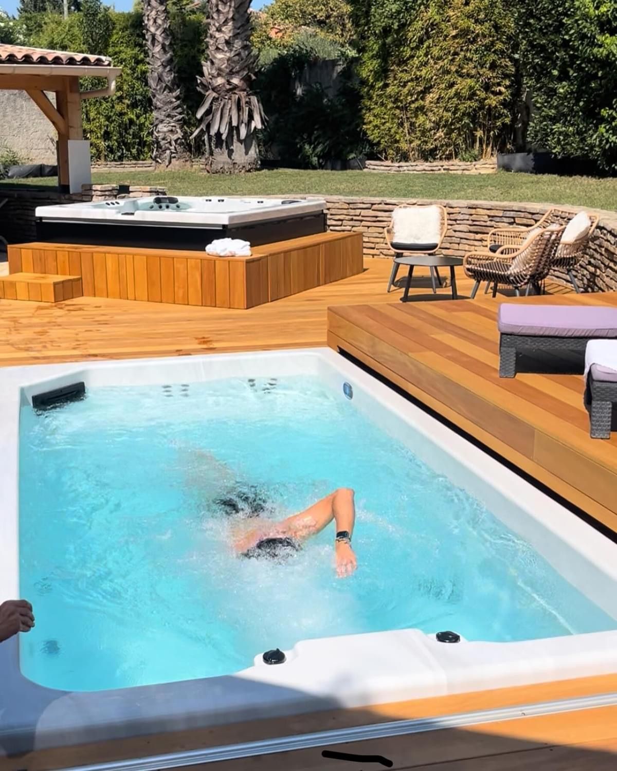 Une personne nage dans une piscine avec un jacuzzi en arrière-plan