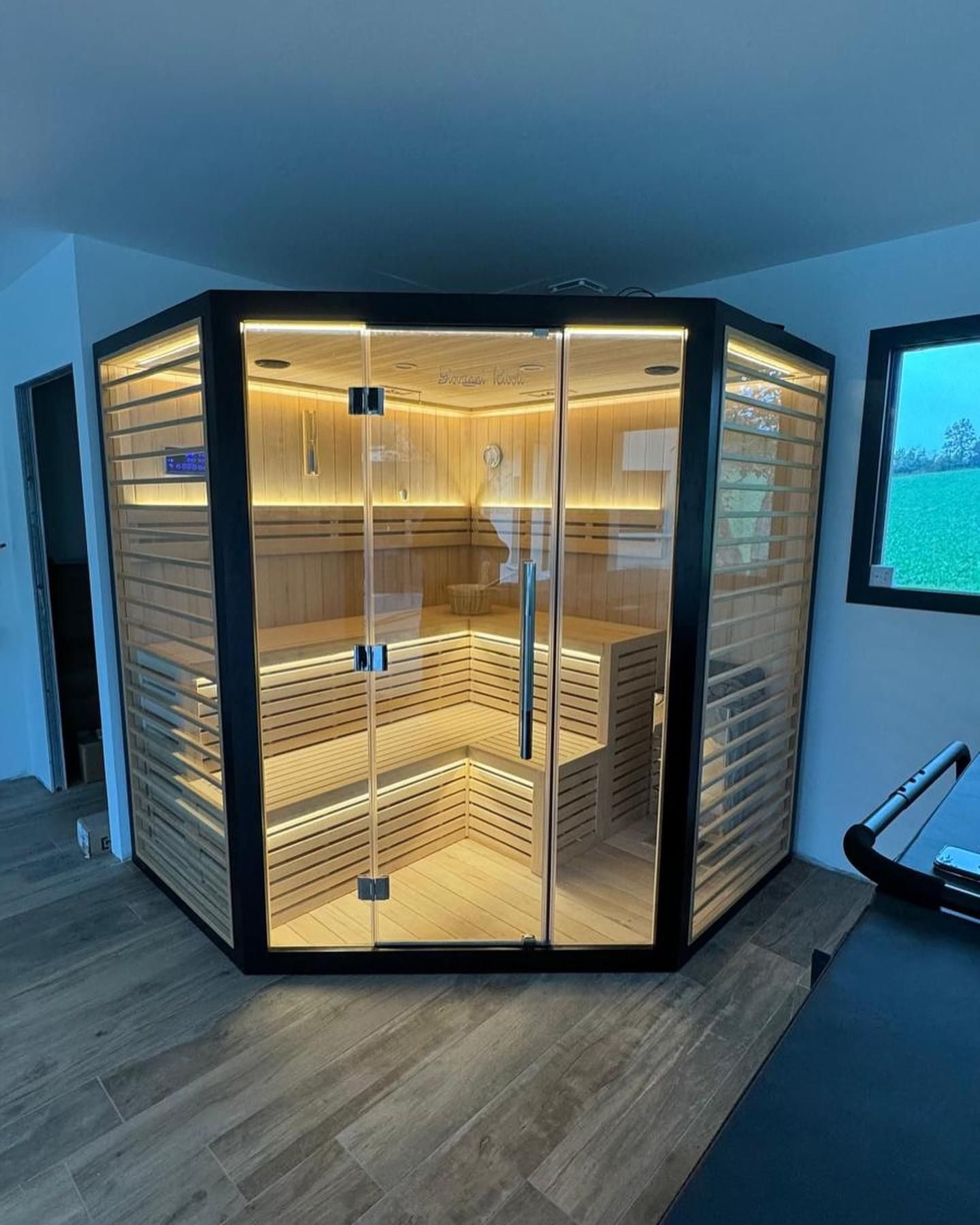 Un sauna est installé dans le coin d'une pièce à côté d'une fenêtre.