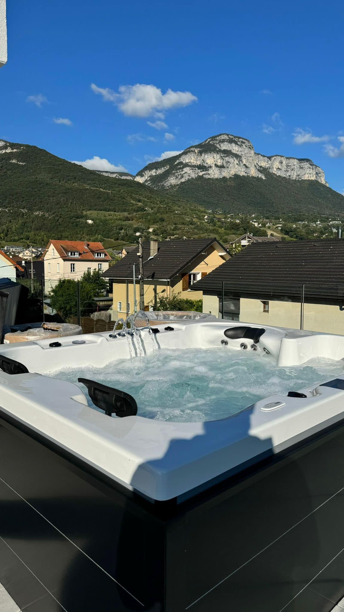 Un bain à remous avec vue sur les montagnes et les maisons en arrière-plan.