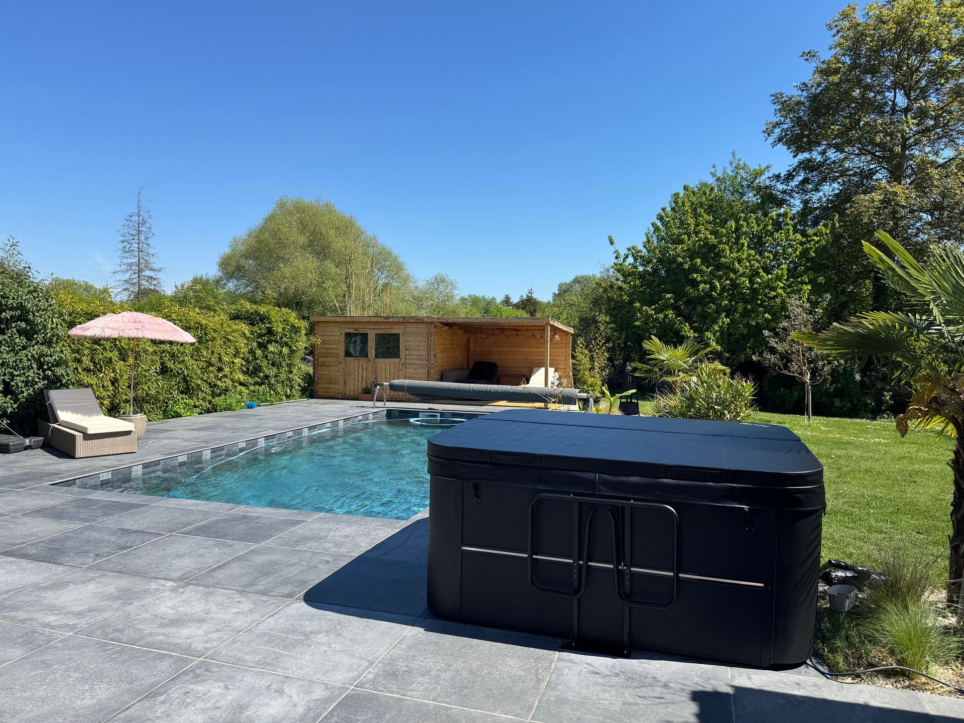 Un jacuzzi est installé à côté d'une piscine devant une maison.
