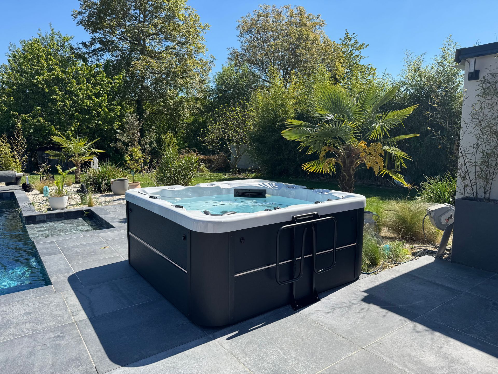 Un bain à remous est installé sur une terrasse à côté d'une piscine.