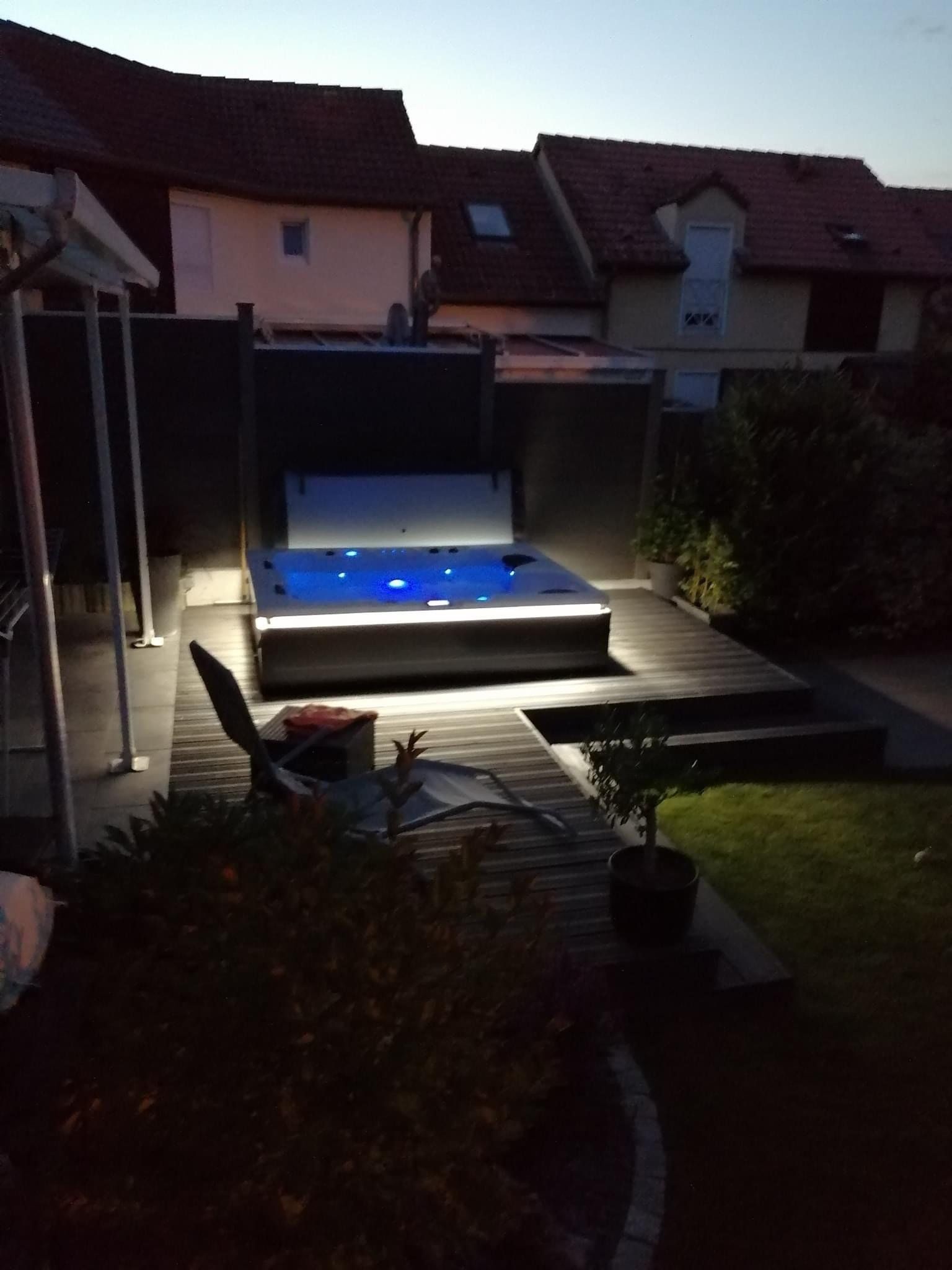 Un jacuzzi est éclairé dans une cour arrière la nuit