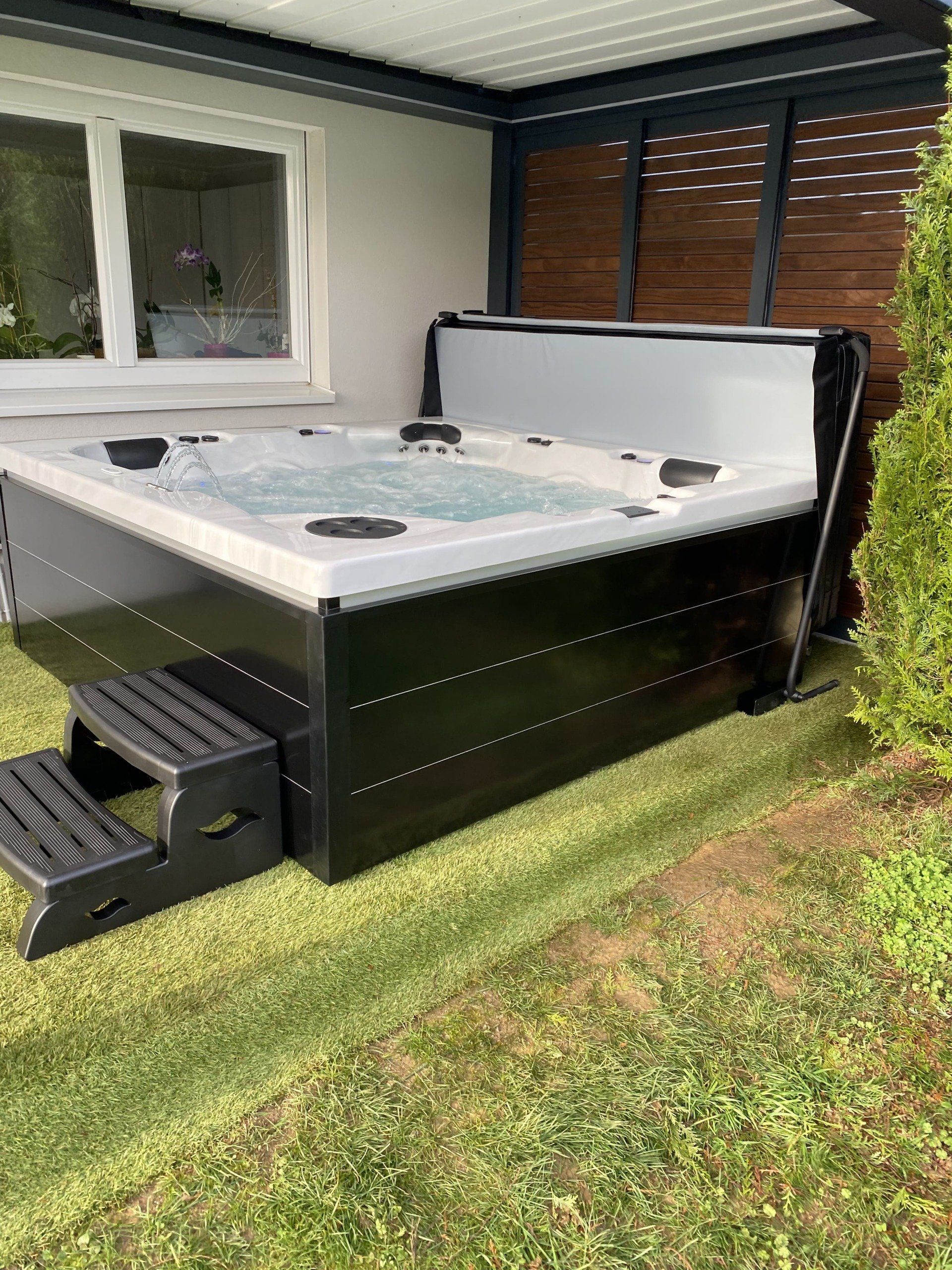 Un jacuzzi est posé dans l'herbe devant une maison.