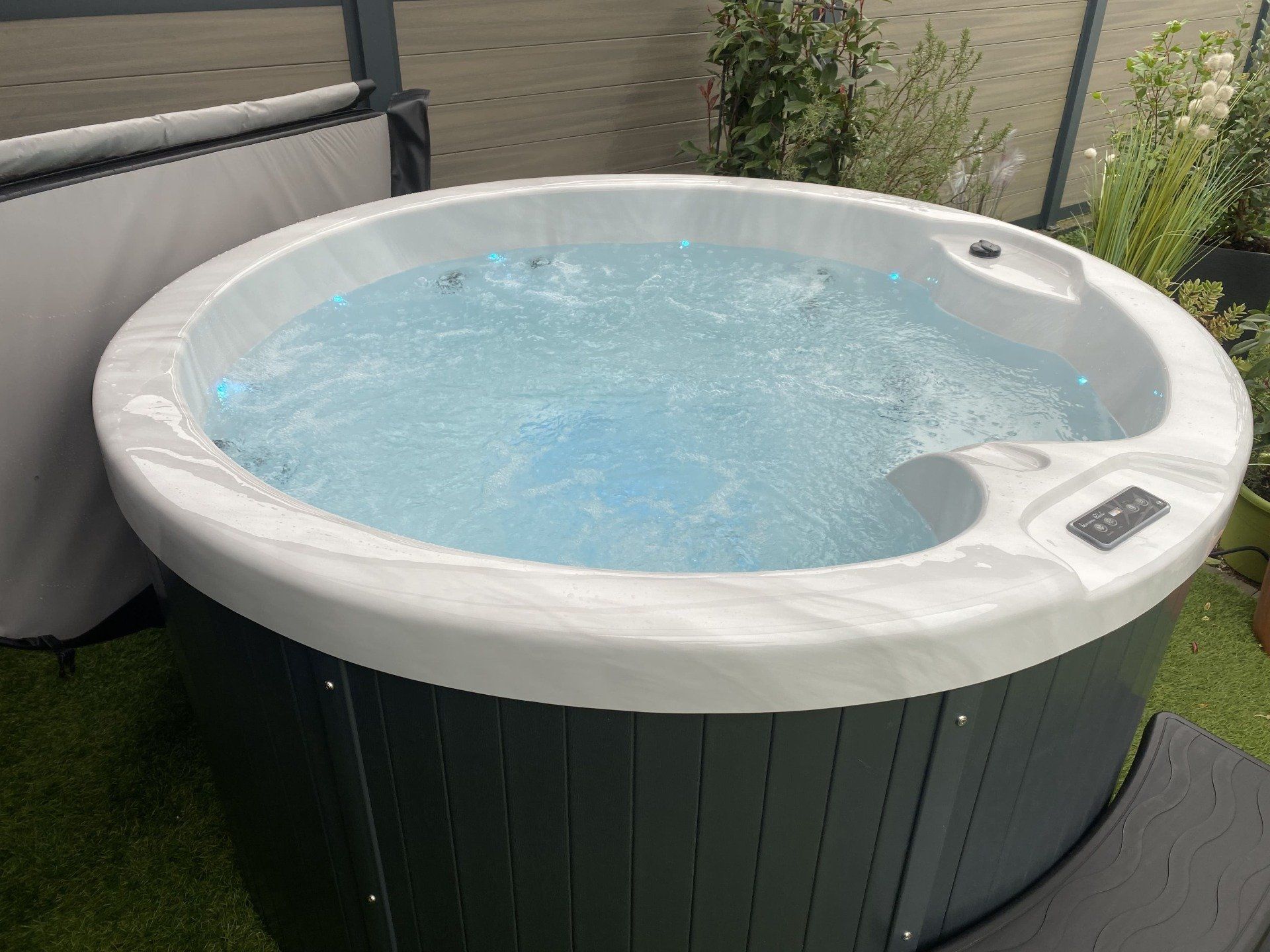 Un bain à remous rond rempli d'eau bleue se trouve sur une terrasse.