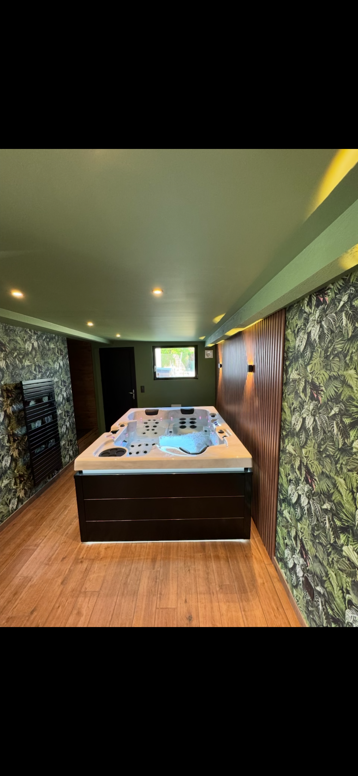 Un grand bain à remous se trouve dans une pièce à côté d'un mur de pierre.