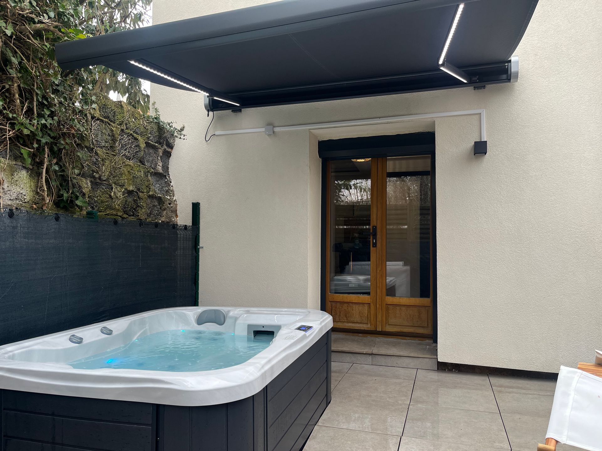 Un bain à remous est installé sous un auvent sur une terrasse.