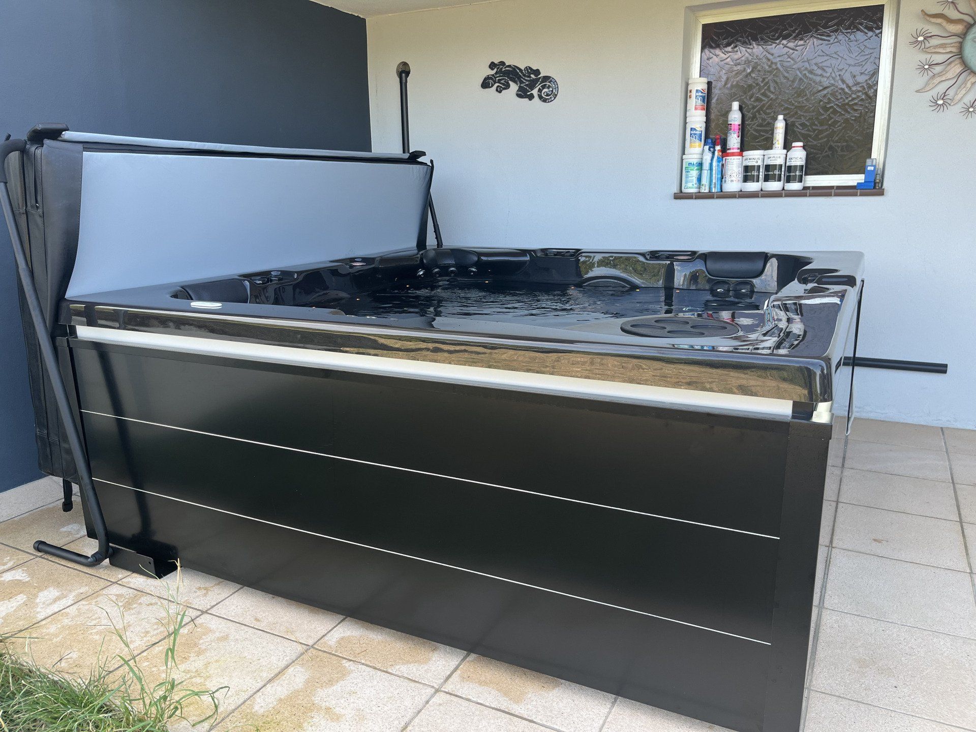 Un jacuzzi noir est posé sur une terrasse à côté d'une fenêtre.