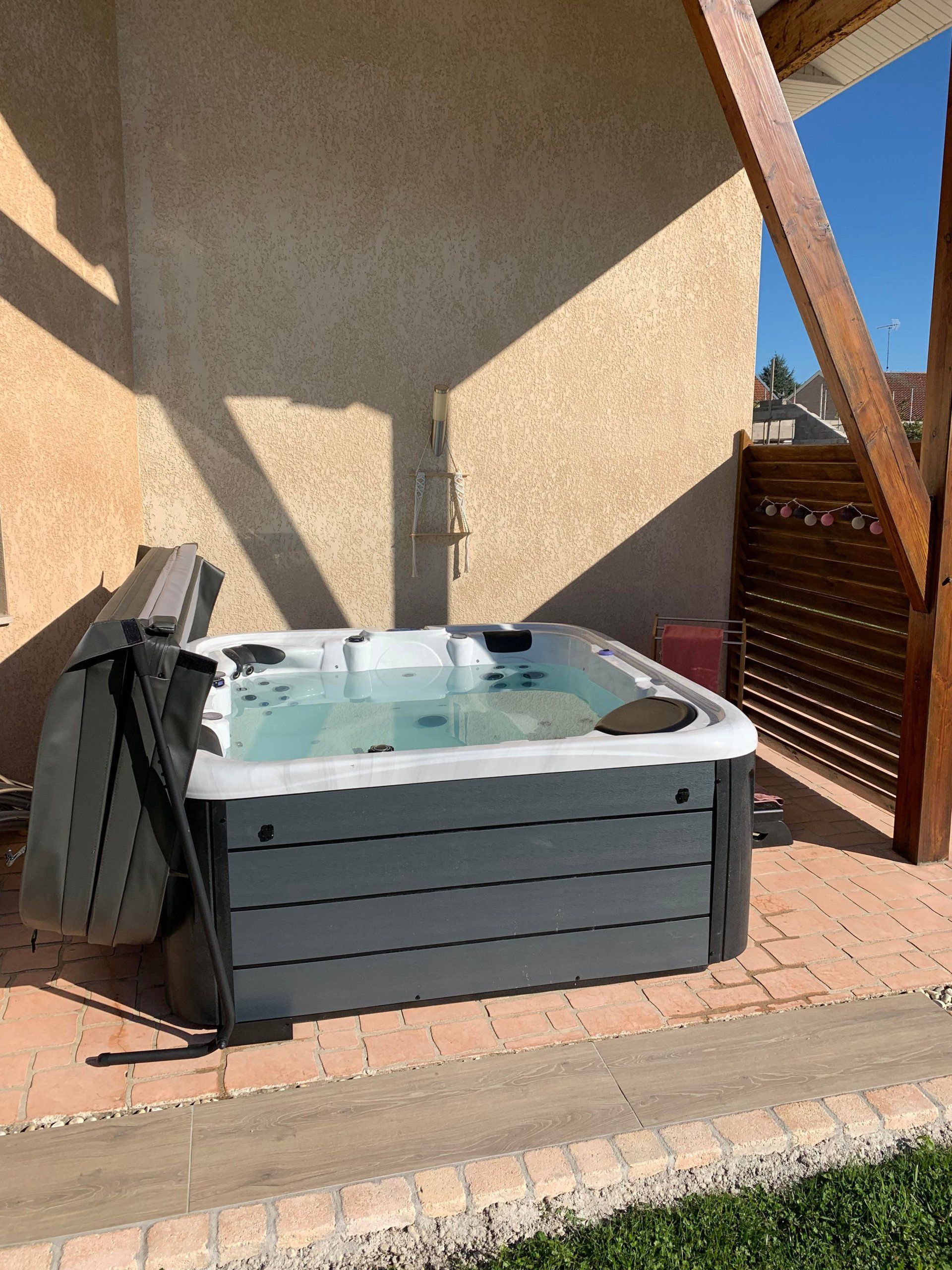 Un bain à remous est installé sur une terrasse à côté d'une maison.