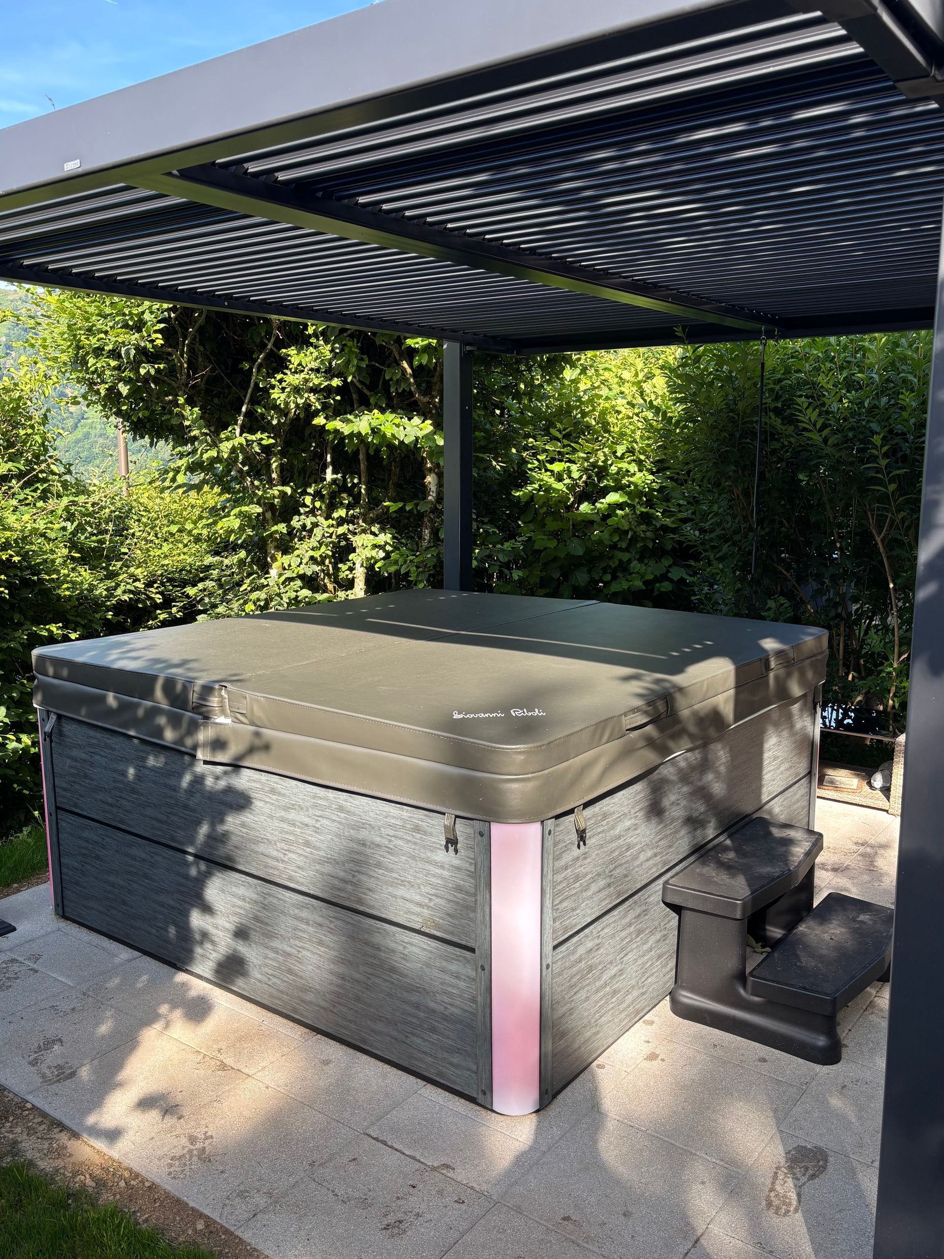 Un bain à remous est installé sous une pergola dans une cour arrière.