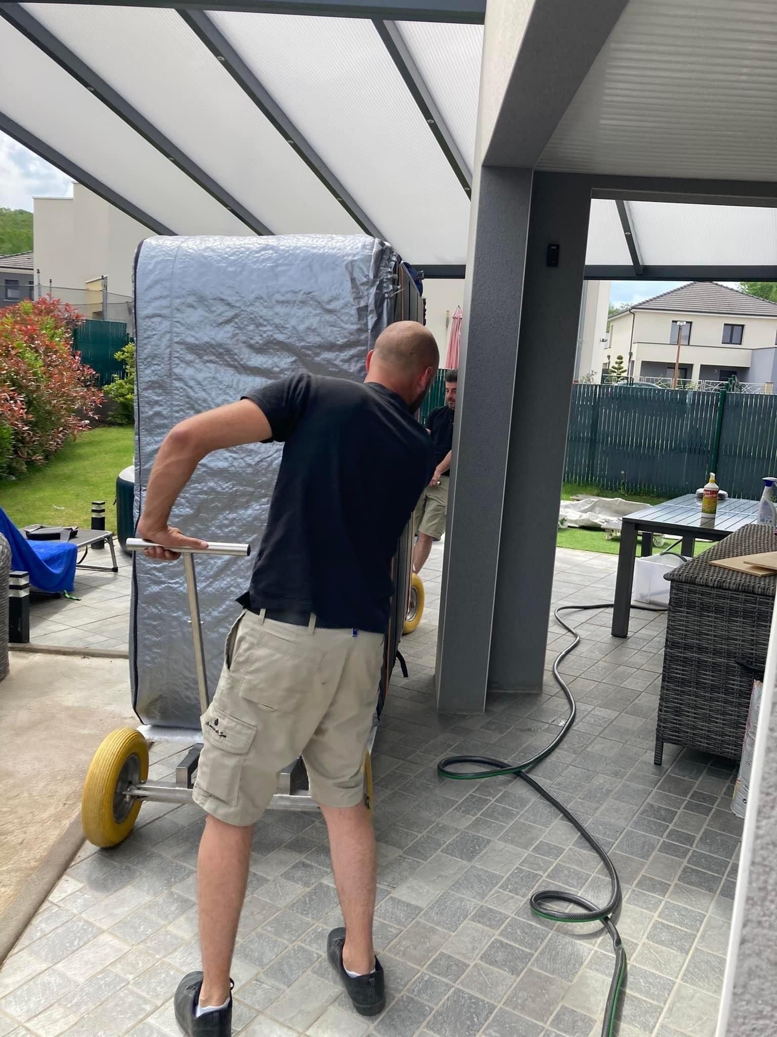 Un homme pousse un gros objet sur un chariot.