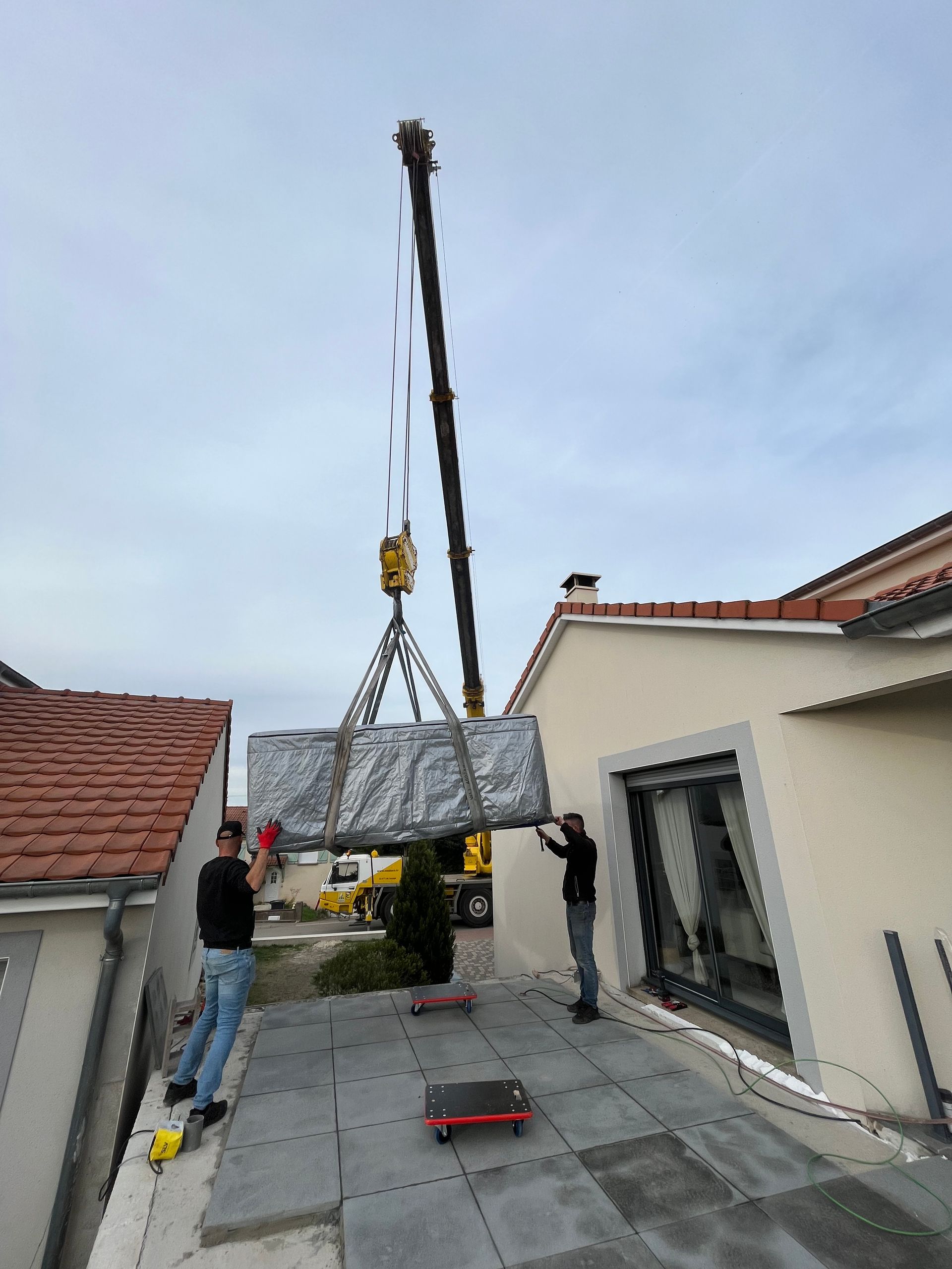 Une grue soulève un gros morceau de métal au sommet d'un bâtiment.