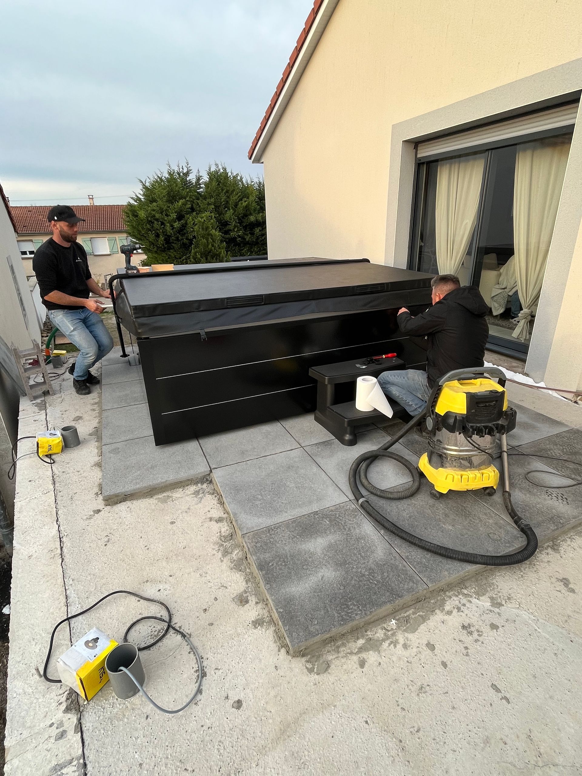 Deux hommes travaillent sur une couverture de piscine sur le toit d'une maison.