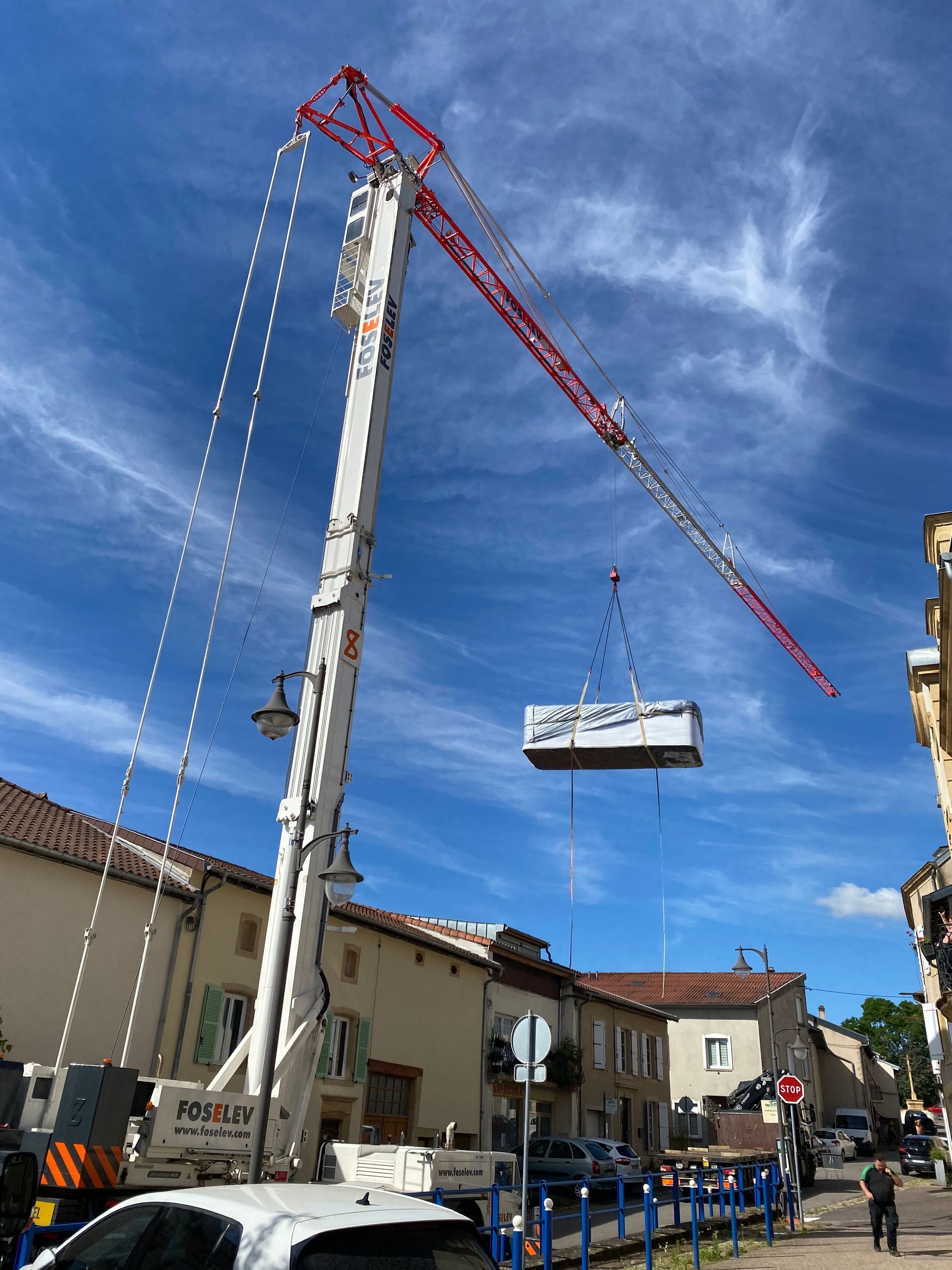 Une grande grue soulève une boîte blanche dans les airs