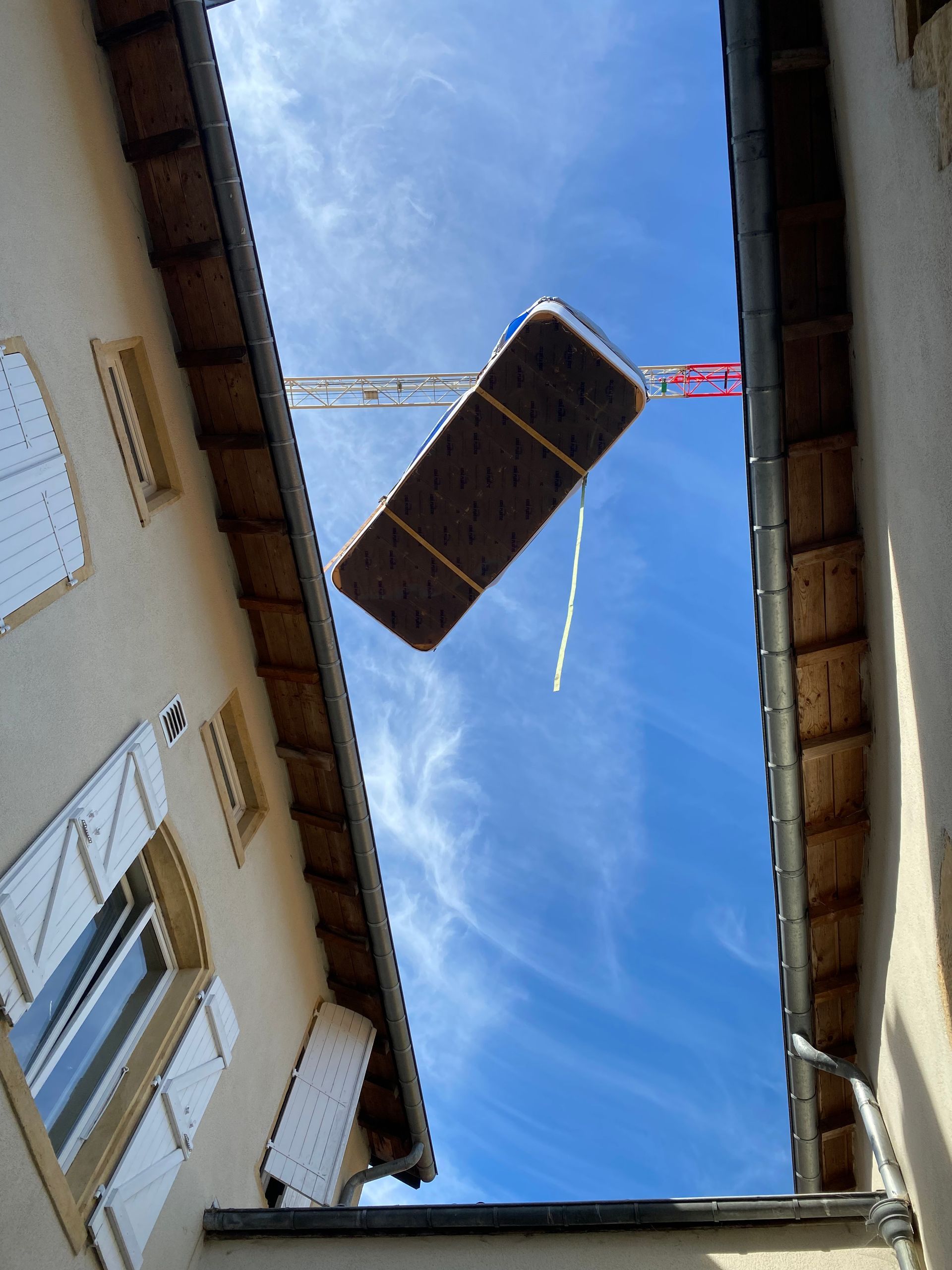 Un gros morceau de bois est soulevé dans les airs par une grue