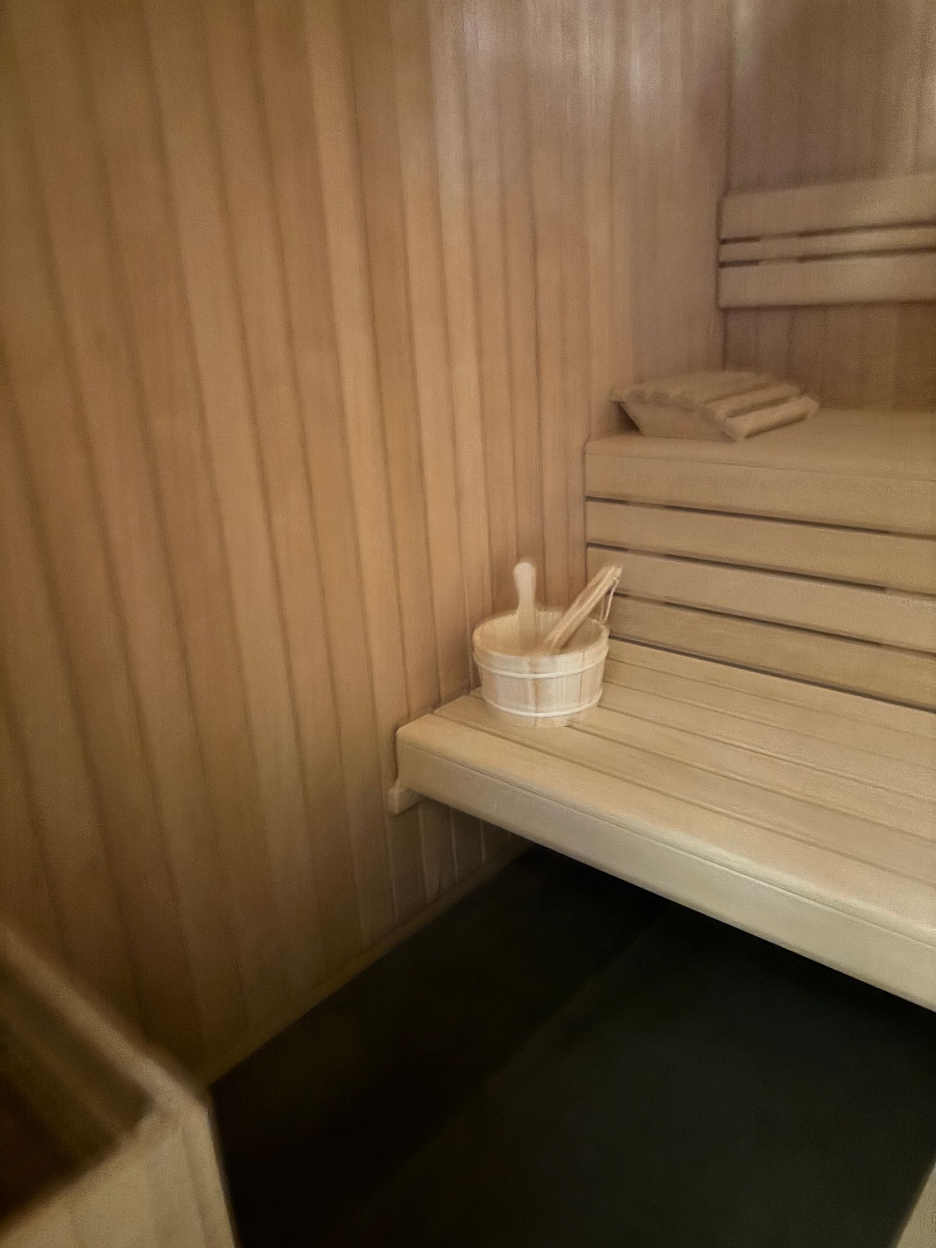 Intérieur de sauna en bois avec seau et louche sur banc.