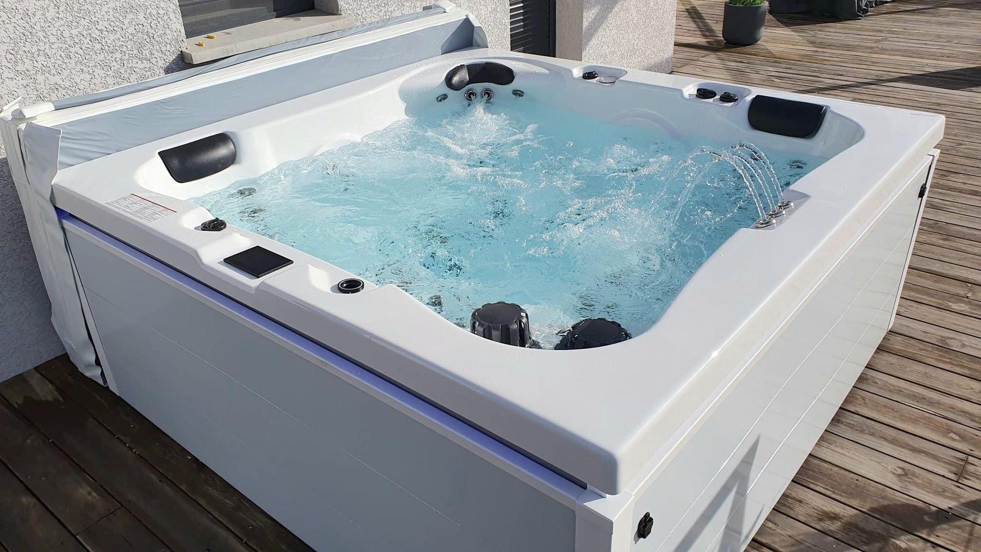 Un bain à remous blanc est posé sur une terrasse en bois.