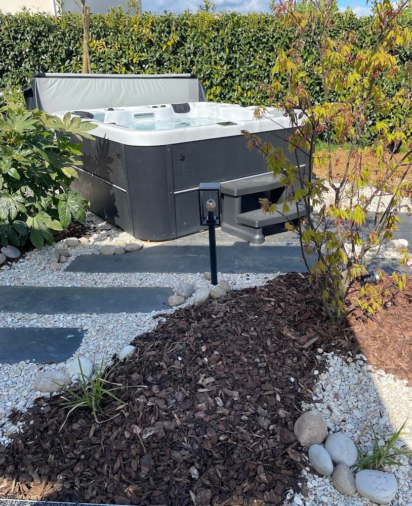 Un jacuzzi est installé au milieu d'un jardin.