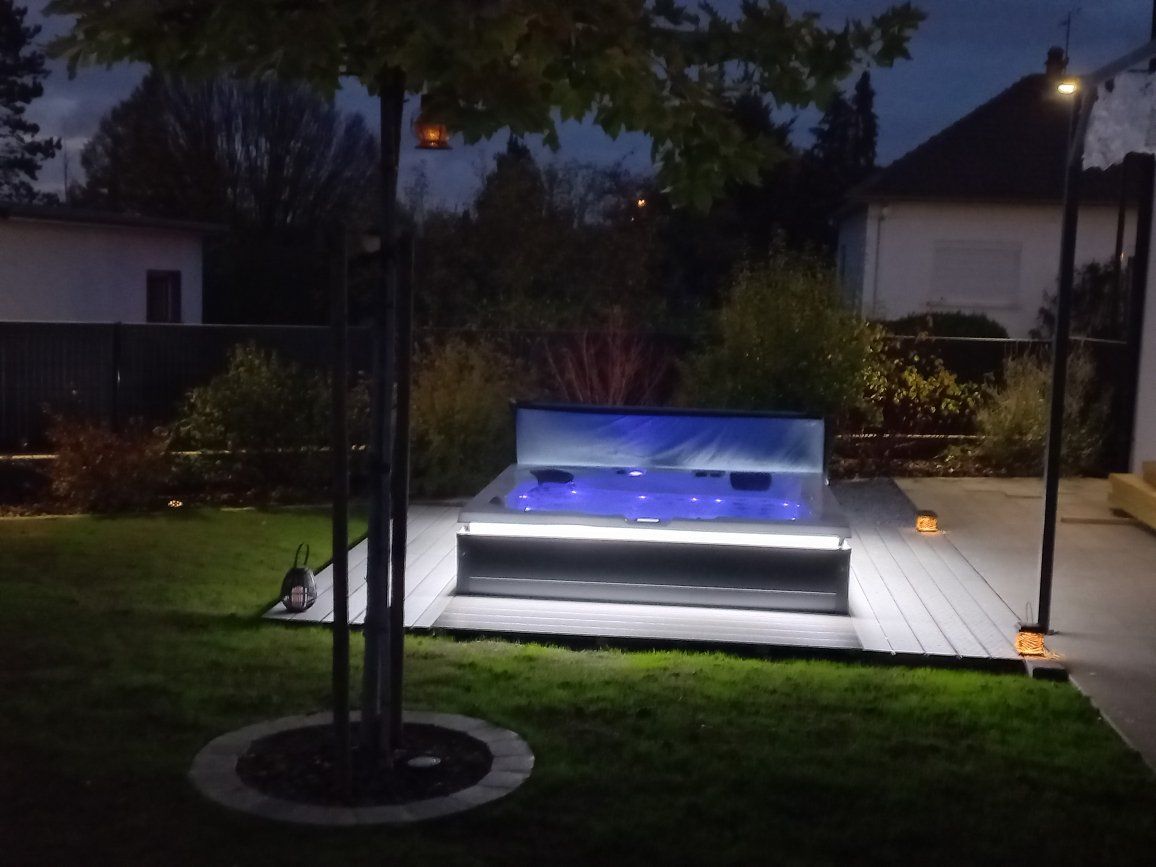 Un jacuzzi est éclairé la nuit dans une cour arrière