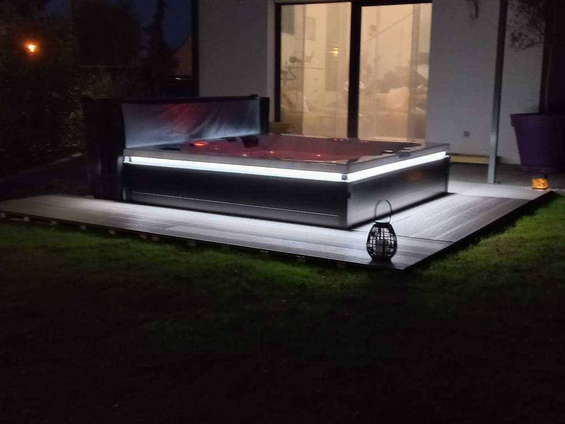 Un jacuzzi est éclairé la nuit devant une maison