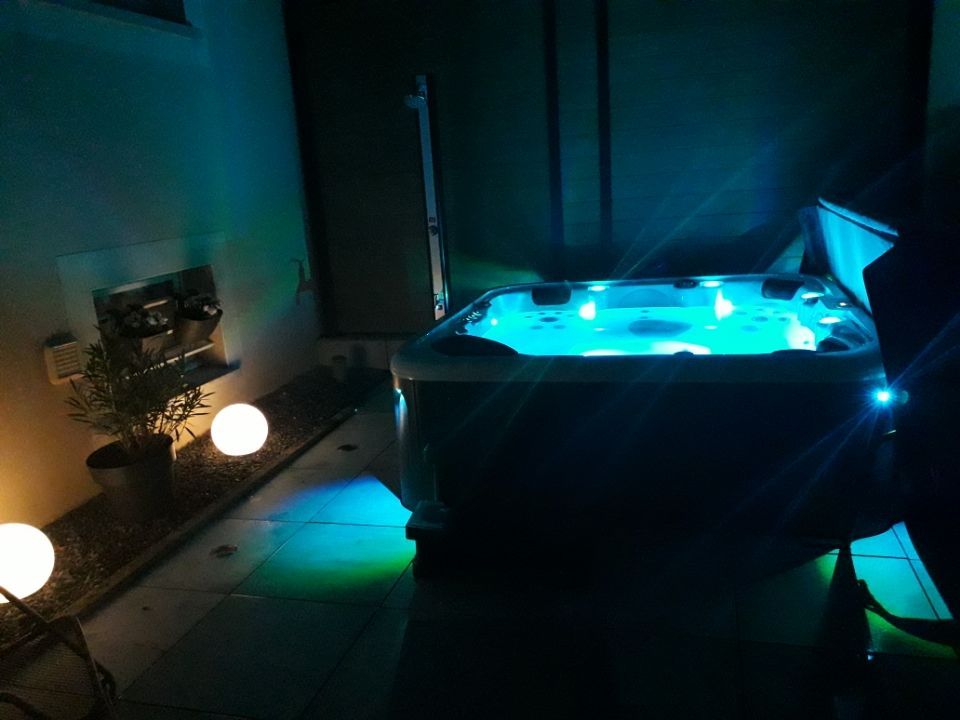 Un bain à remous est éclairé la nuit dans une pièce sombre.