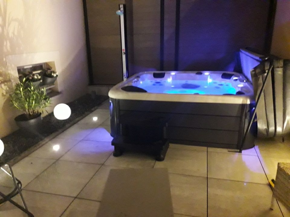 Un bain à remous est posé sur un sol carrelé dans une pièce.