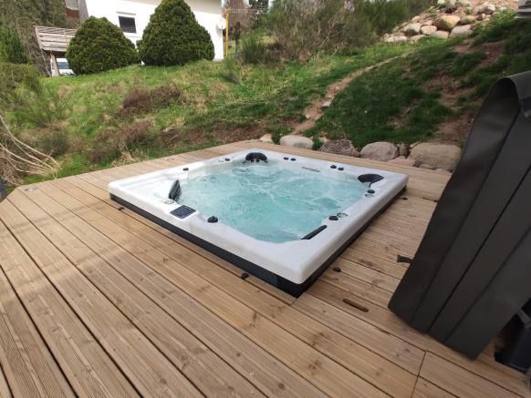 Un bain à remous est posé sur une terrasse en bois.