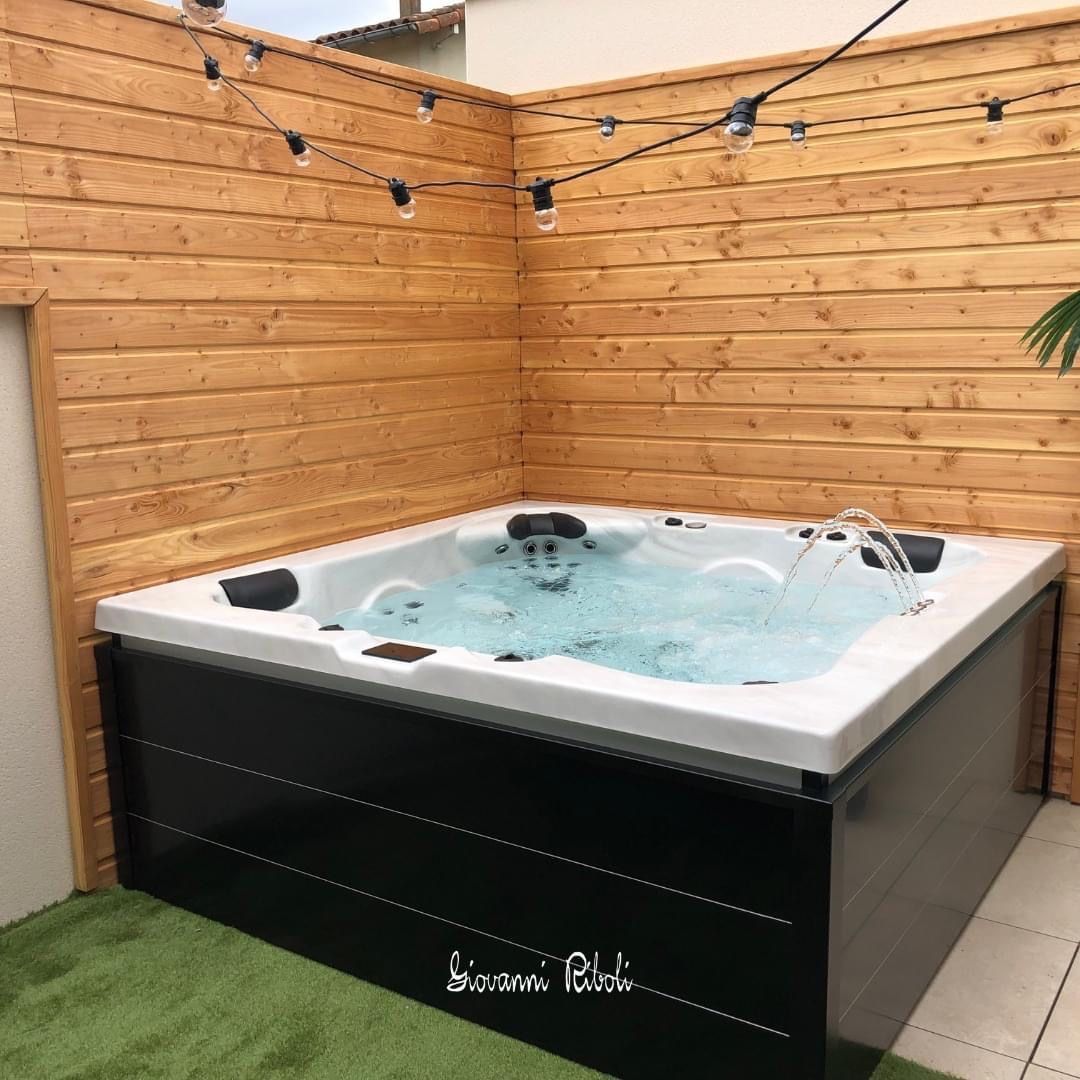 Un bain à remous est assis dans le coin d'une clôture en bois.