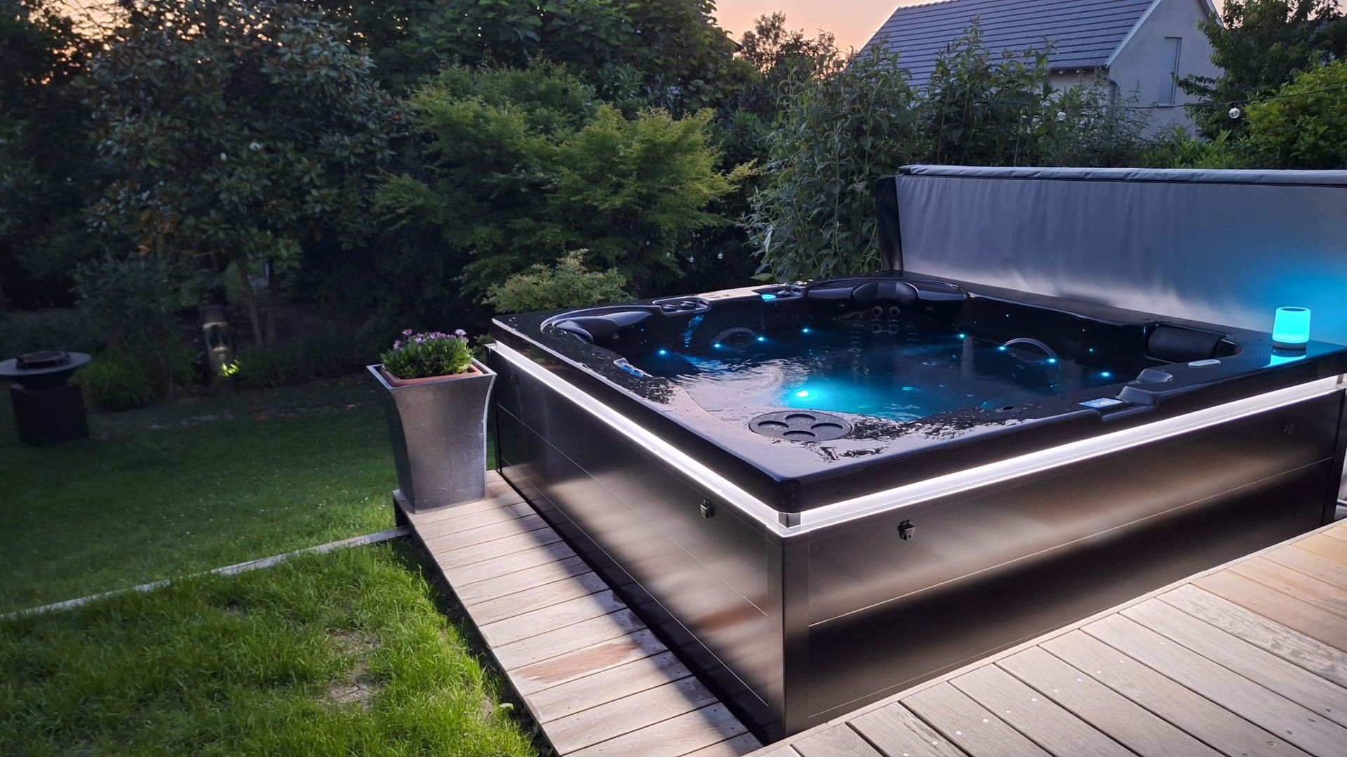 Un jacuzzi noir est posé sur une terrasse en bois