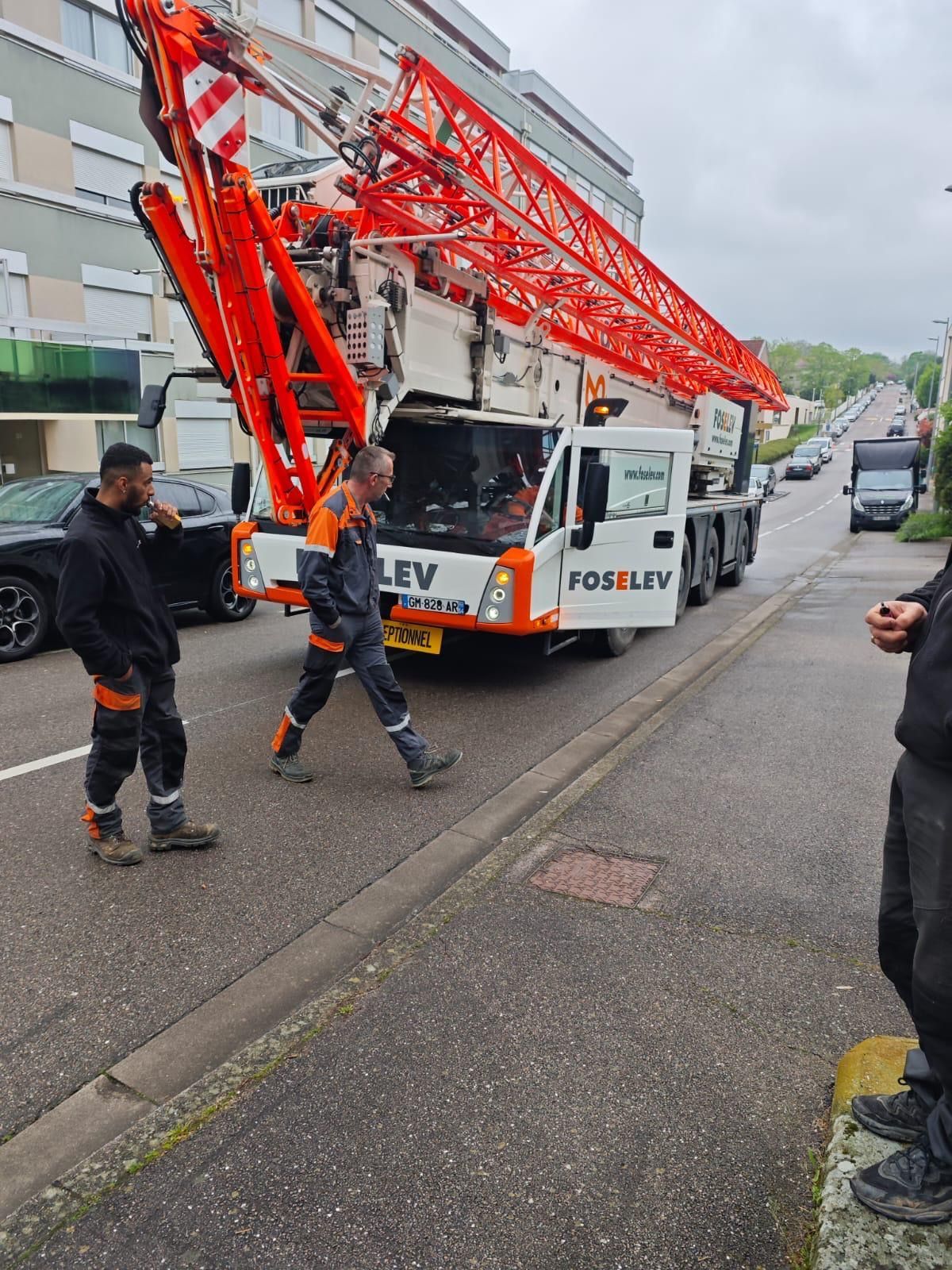 Un homme se tient à côté d'une grue sur le bord de la route.