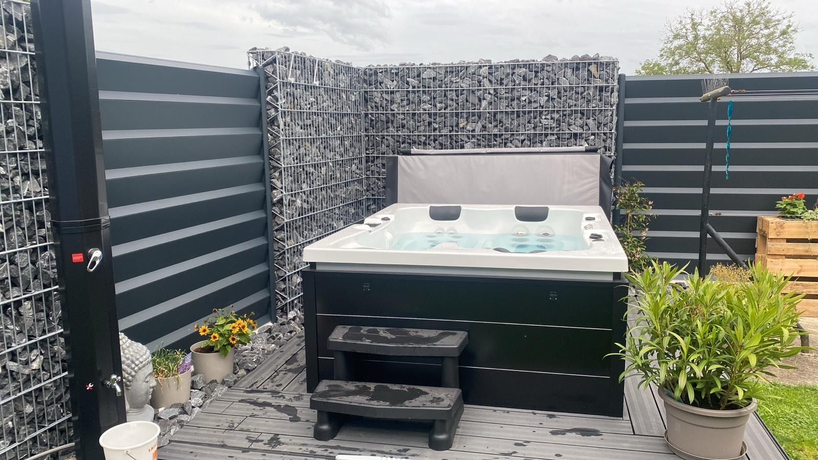 Un bain à remous est installé dans une cour arrière à côté d'une clôture.