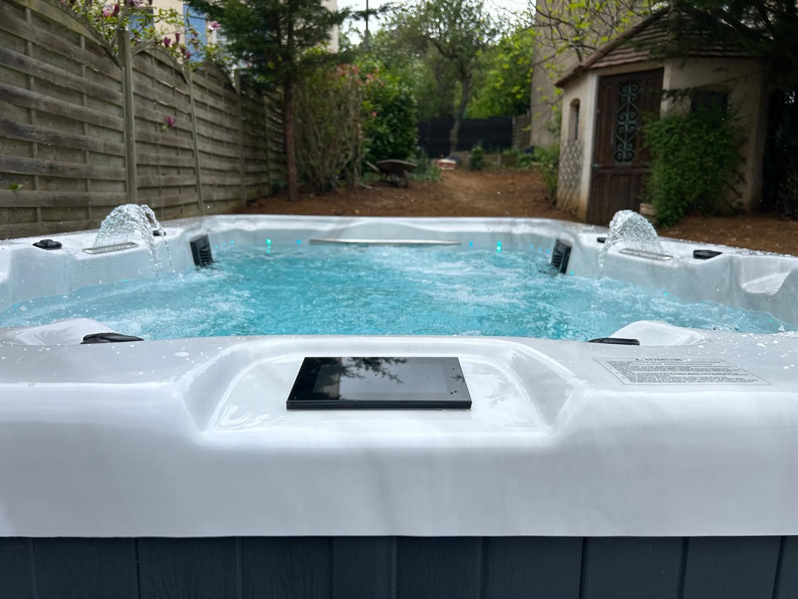 Un bain à remous est installé dans l'arrière-cour à côté d'une clôture en bois.