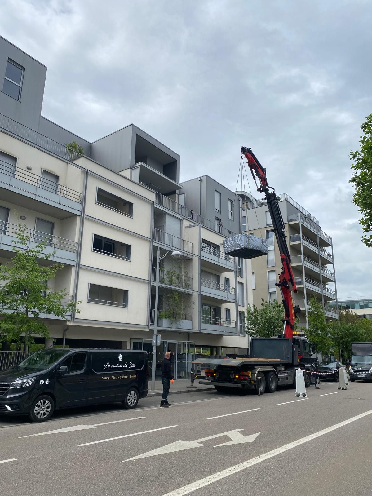 Un camion avec une grue à l'arrière est garé devant un bâtiment.