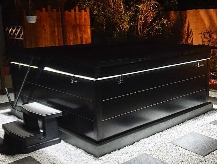 Un jacuzzi noir avec des escaliers qui y mènent