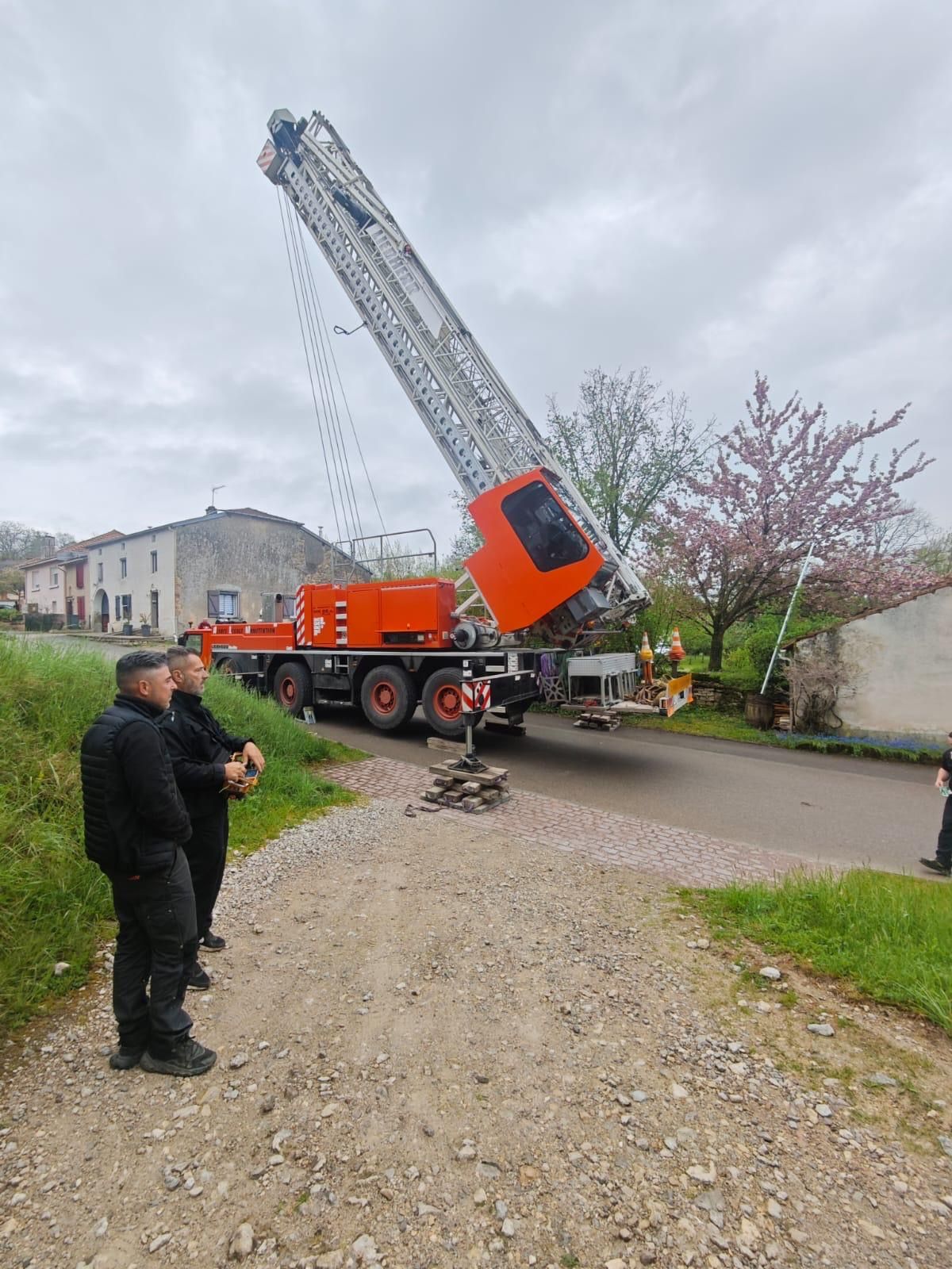 Un groupe d'hommes se tient à côté d'une grue sur le bord d'une route.