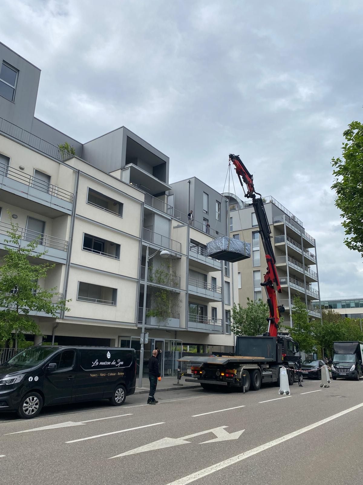 Un camion avec une grue attachée est garé devant un bâtiment.