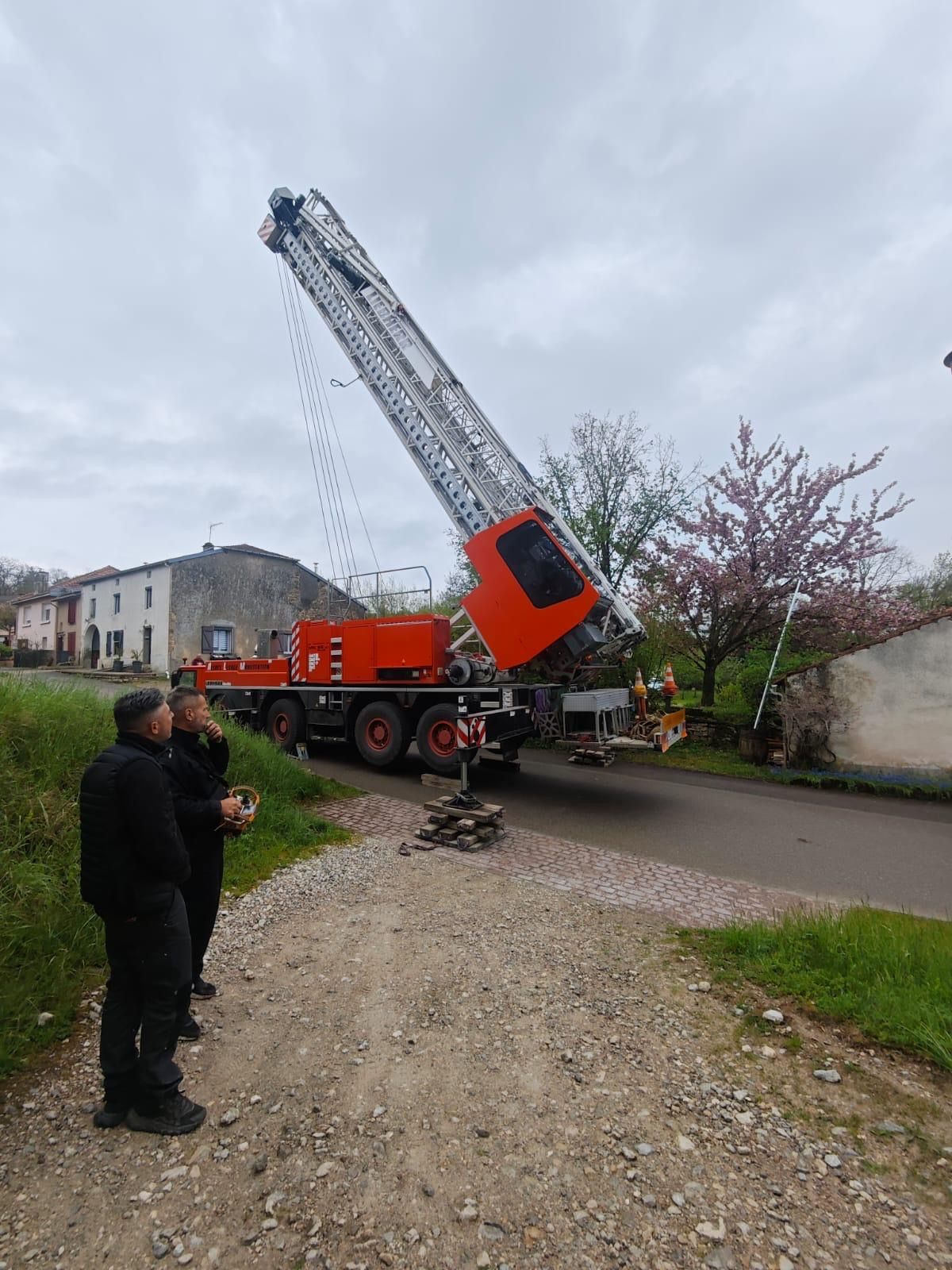 Deux hommes se tiennent à côté d'une grue sur le bord d'une route.