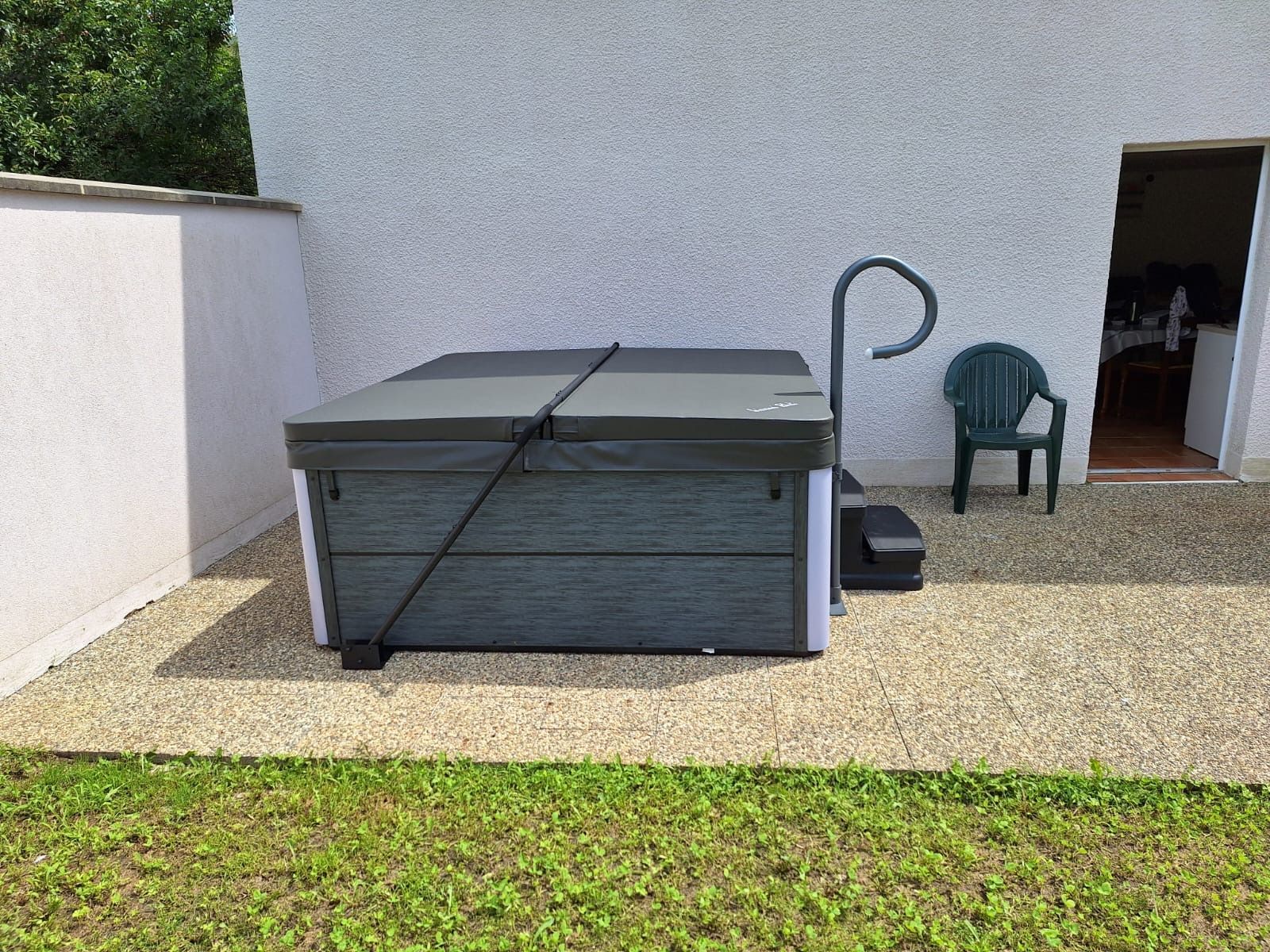 Un jacuzzi est posé dans l'herbe devant un bâtiment.