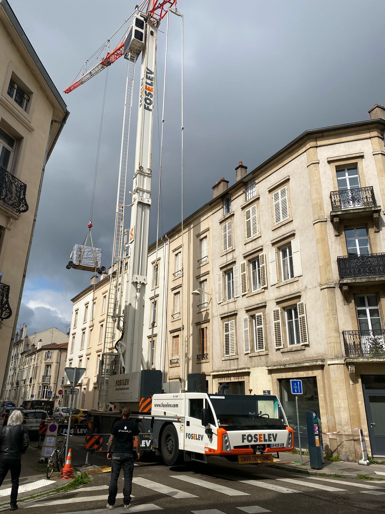 Un camion avec une grue dessus est garé devant un bâtiment.