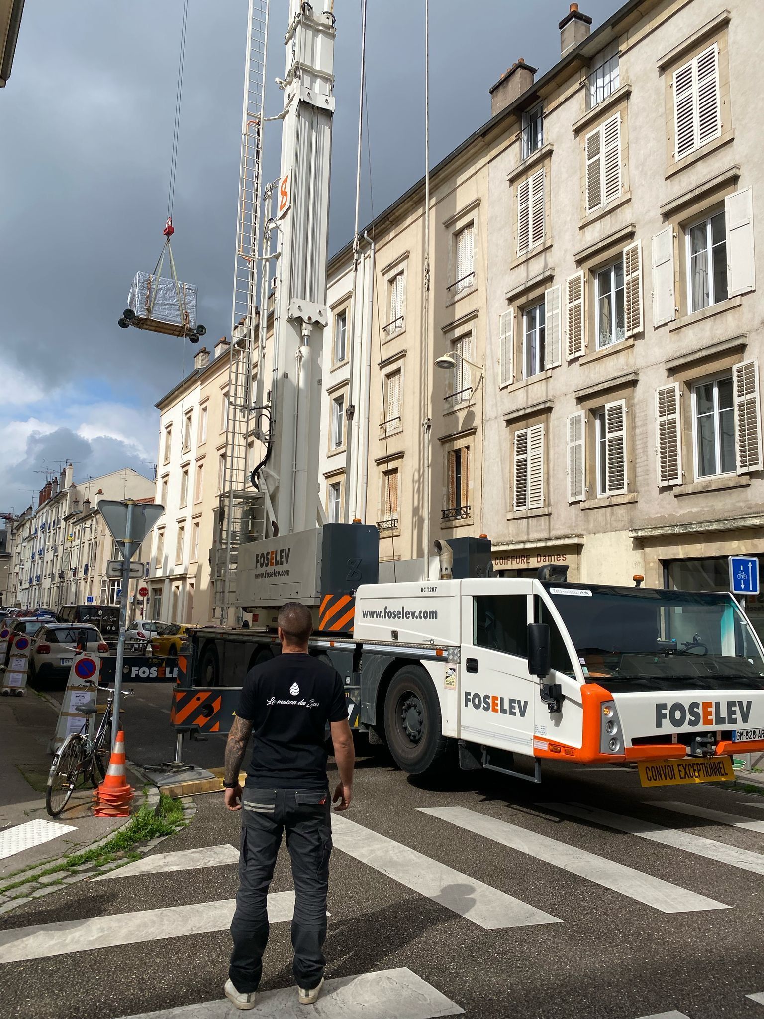 Un homme se tient devant un camion avec une grue dessus.
