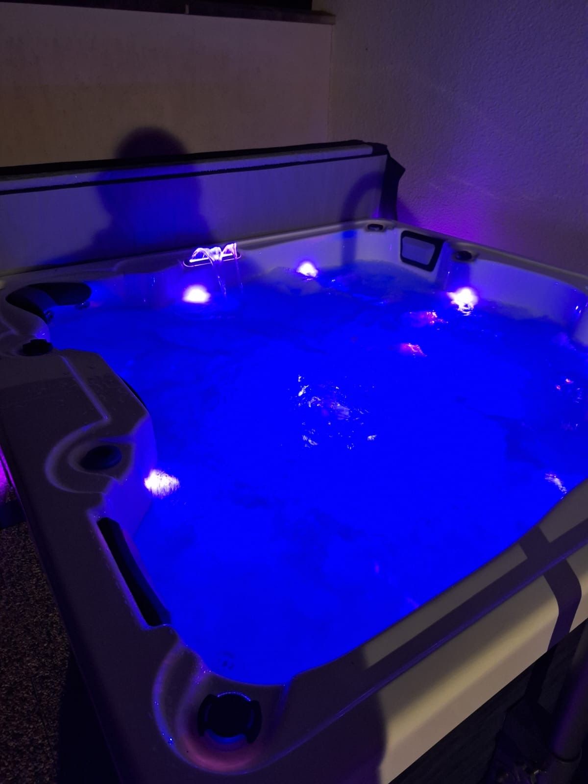 Un bain à remous est éclairé par des lumières bleues la nuit.